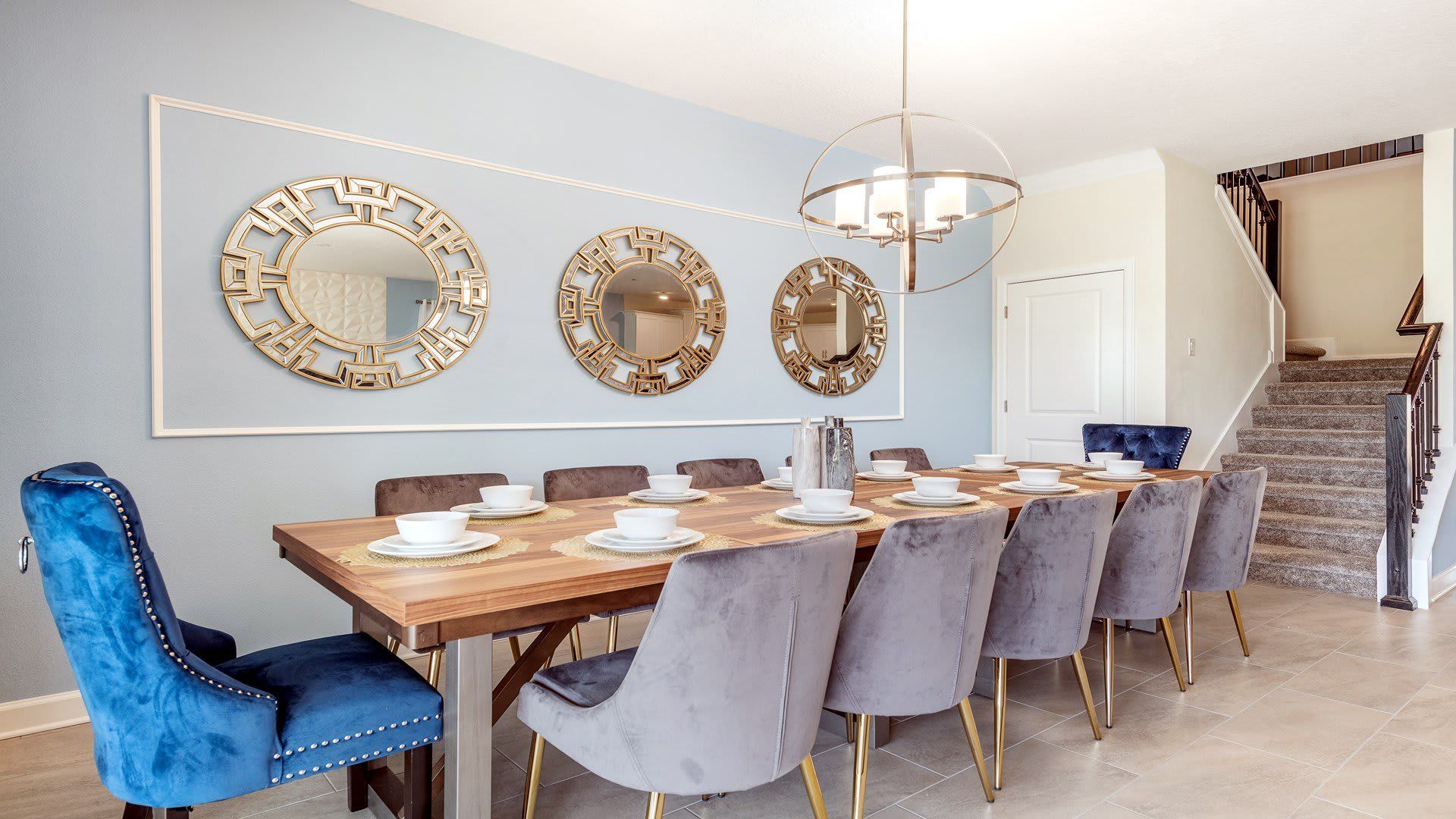 Elegant dining area with luxe blue chairs and stylish mirrors.
