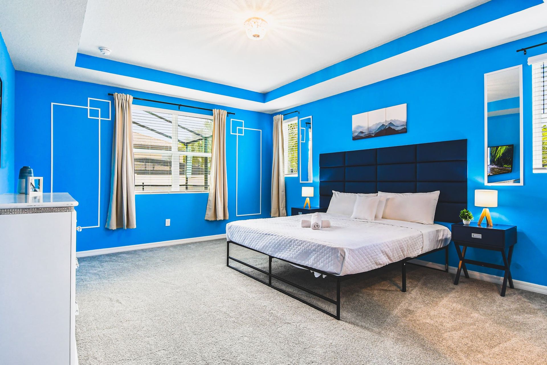 Spacious king suite with bold blue accents, natural light, and modern comfort.