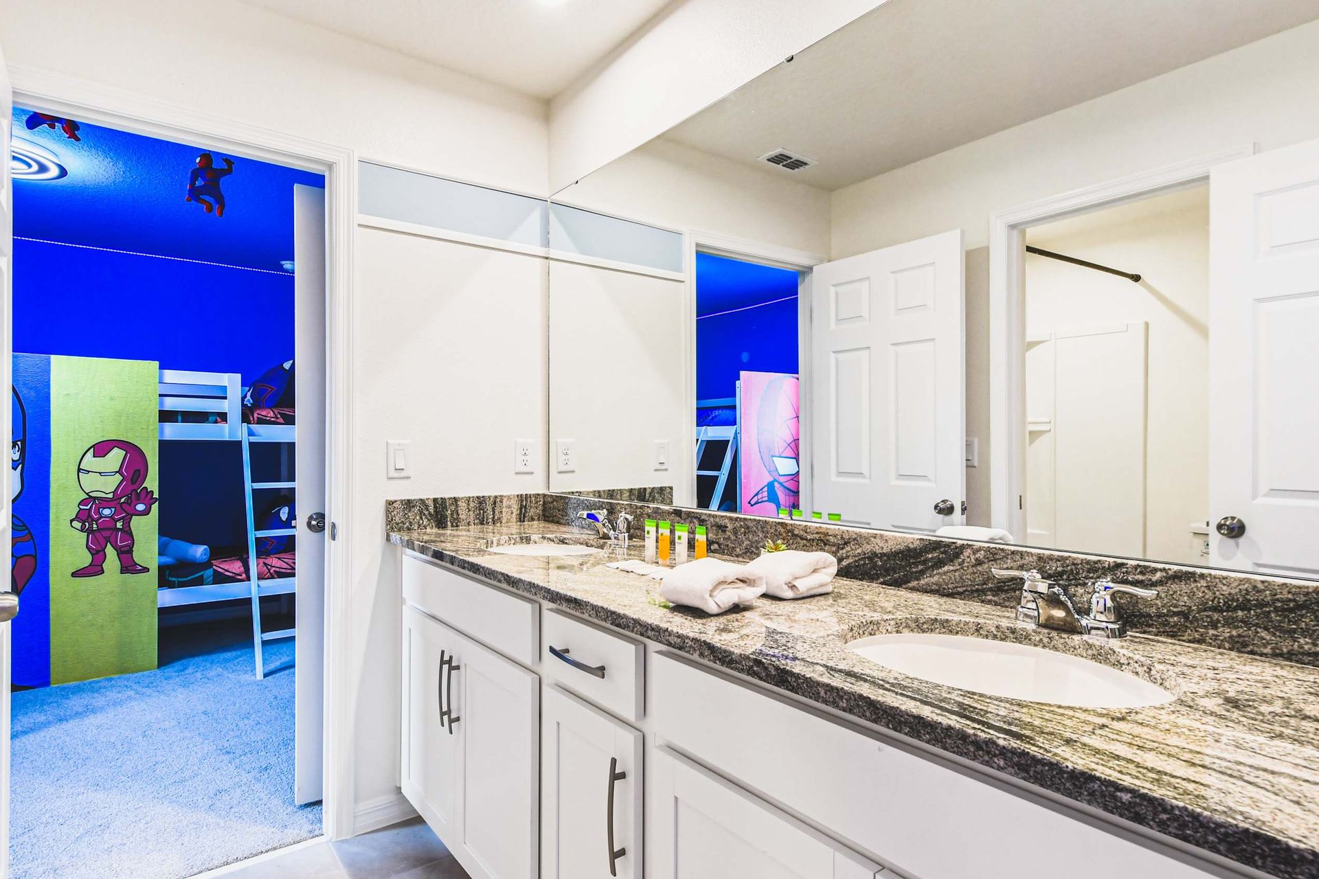 Bathroom with dual sinks, granite countertop, and access to themed kids' room.
