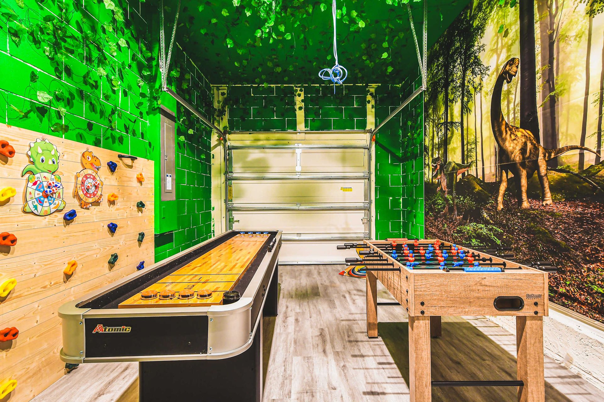 Dinosaur-themed game room with foosball, shuffleboard, and climbing fun.