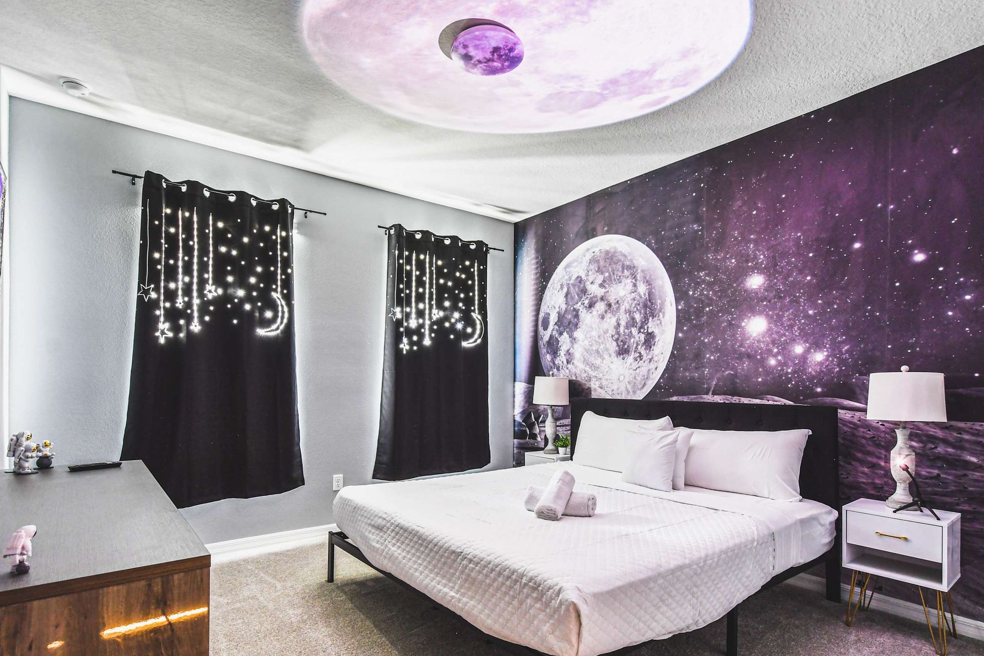 Space-themed bedroom with moonlight ceiling, starry decor, and cozy cosmic charm.