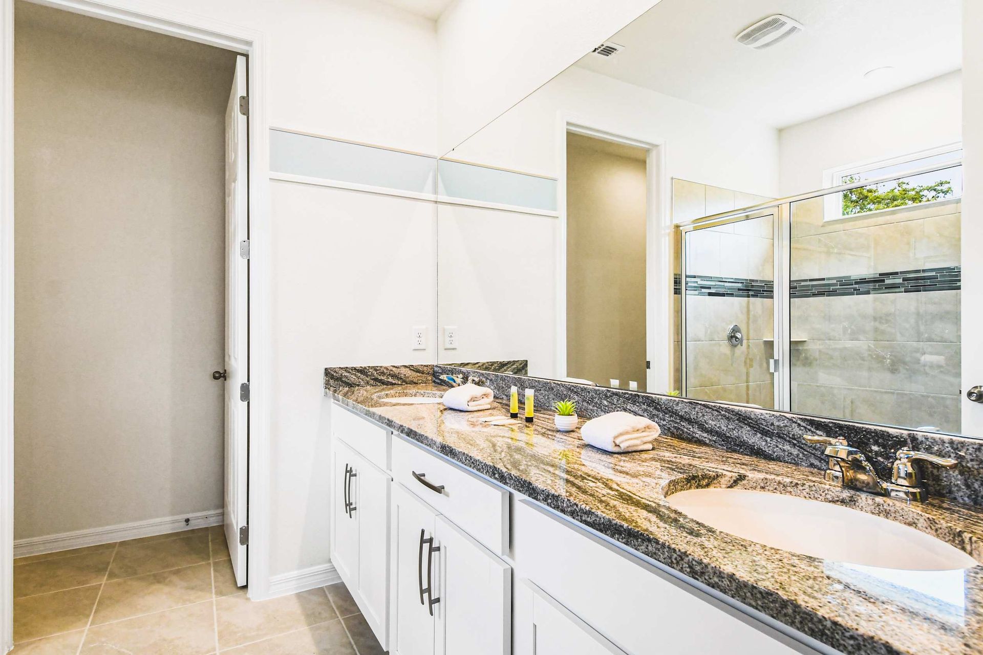 Spacious double vanity with granite counters and a modern walk-in shower.