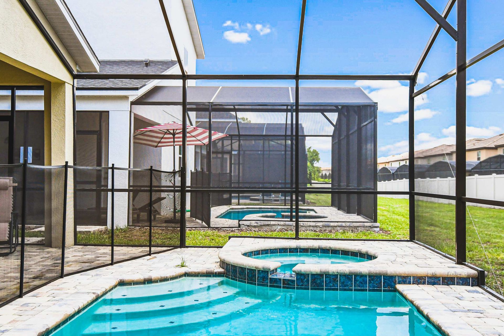 Private screened pool and spa with sunny deck, loungers, and peaceful backyard views.
