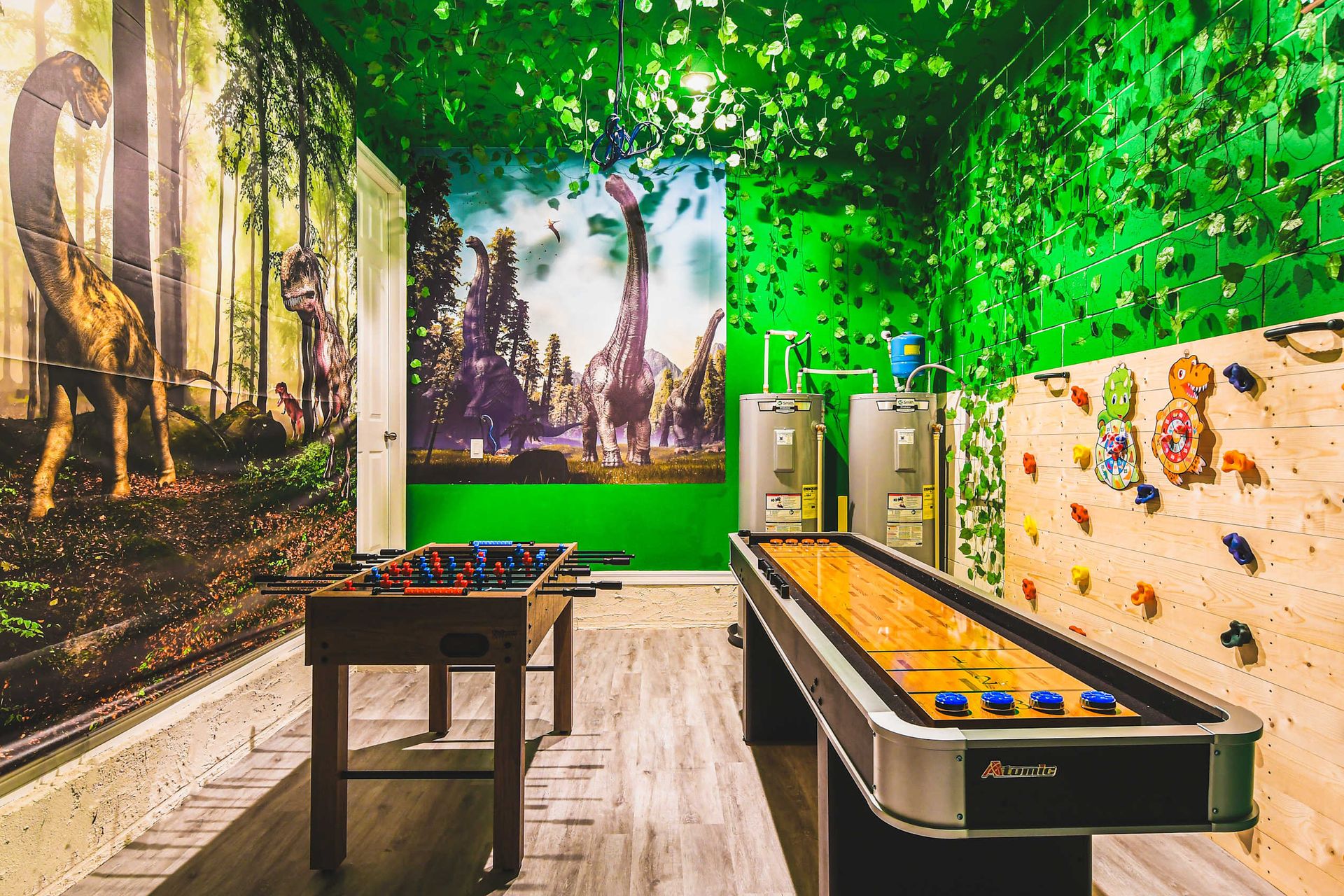Dinosaur-themed game room with foosball, shuffleboard, and climbing fun.