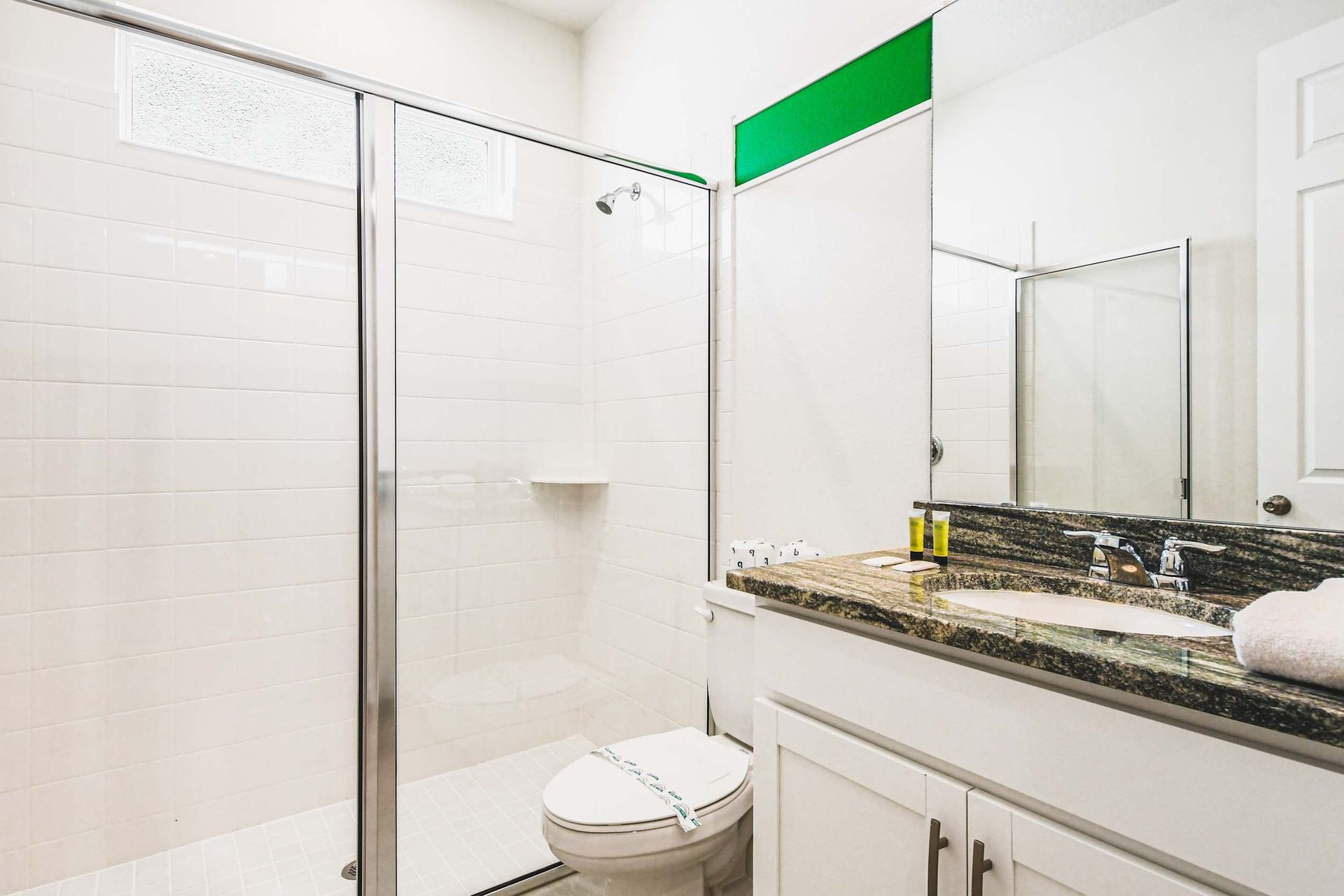 Bright bathroom with a granite countertop and spacious glass-enclosed shower.
