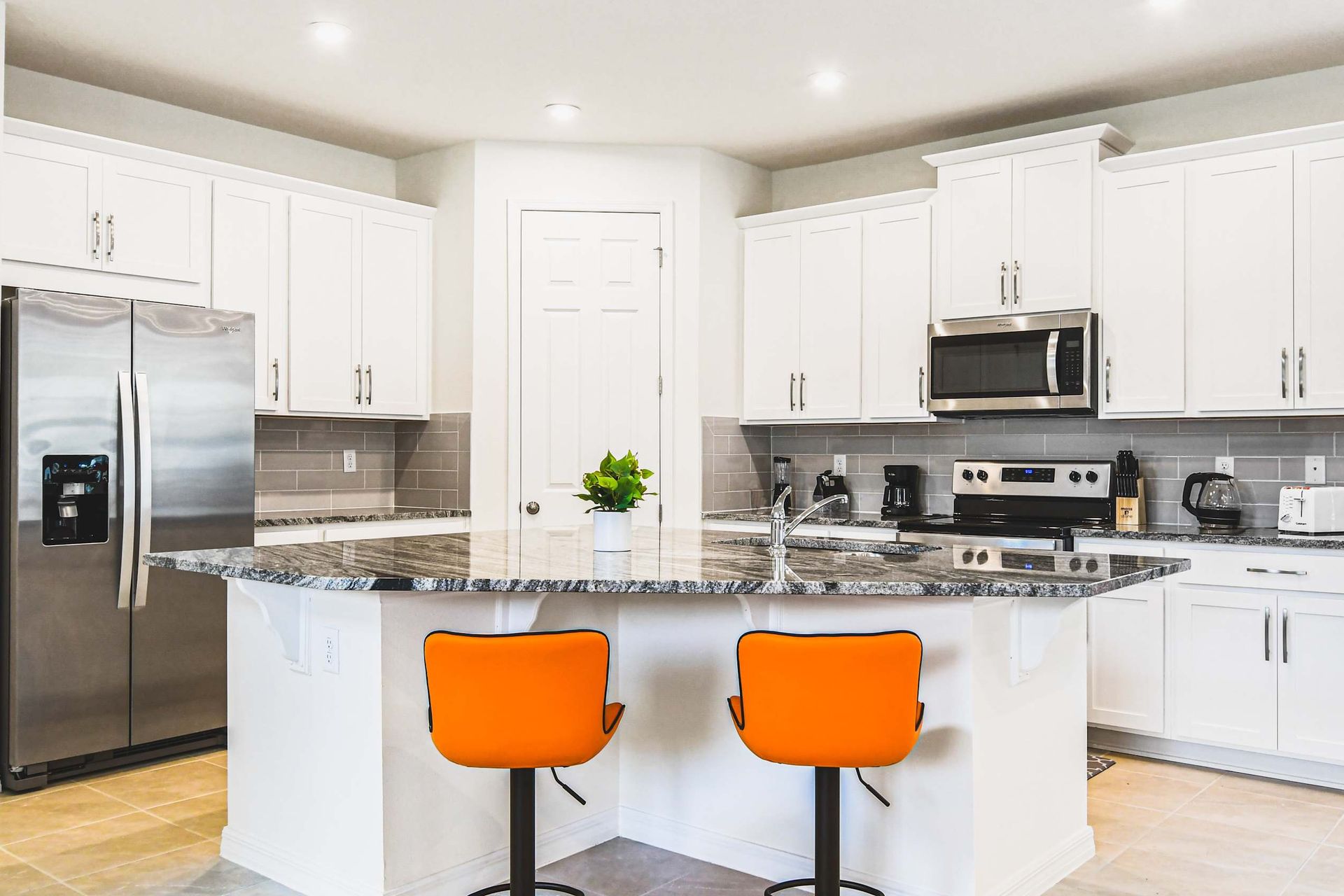 Modern kitchen with granite counters, stainless appliances, and vibrant accents.