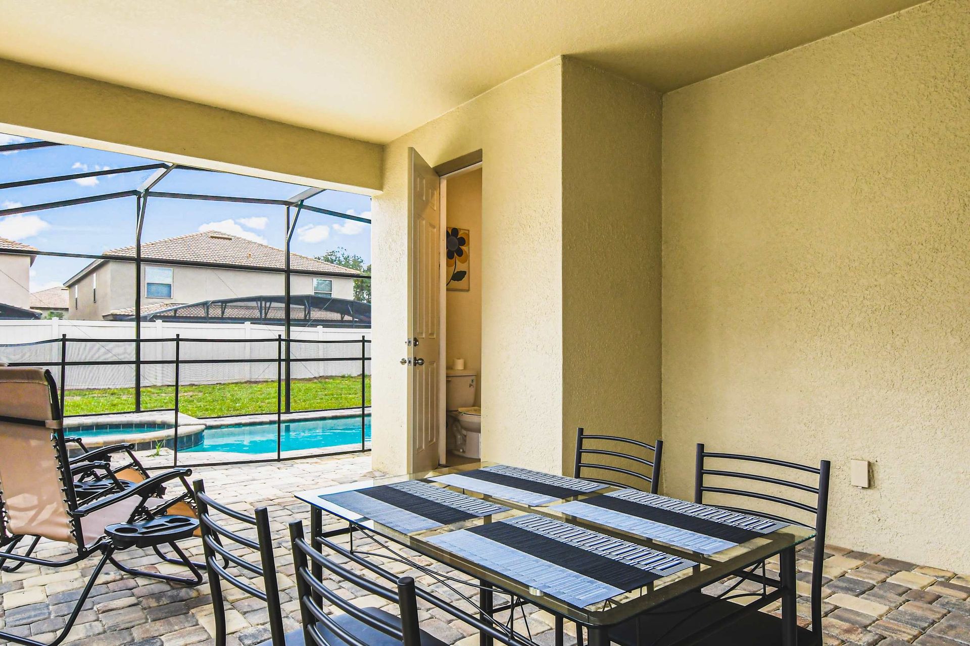 Outdoor dining by the pool with a private bathroom and sunny screened lanai.
