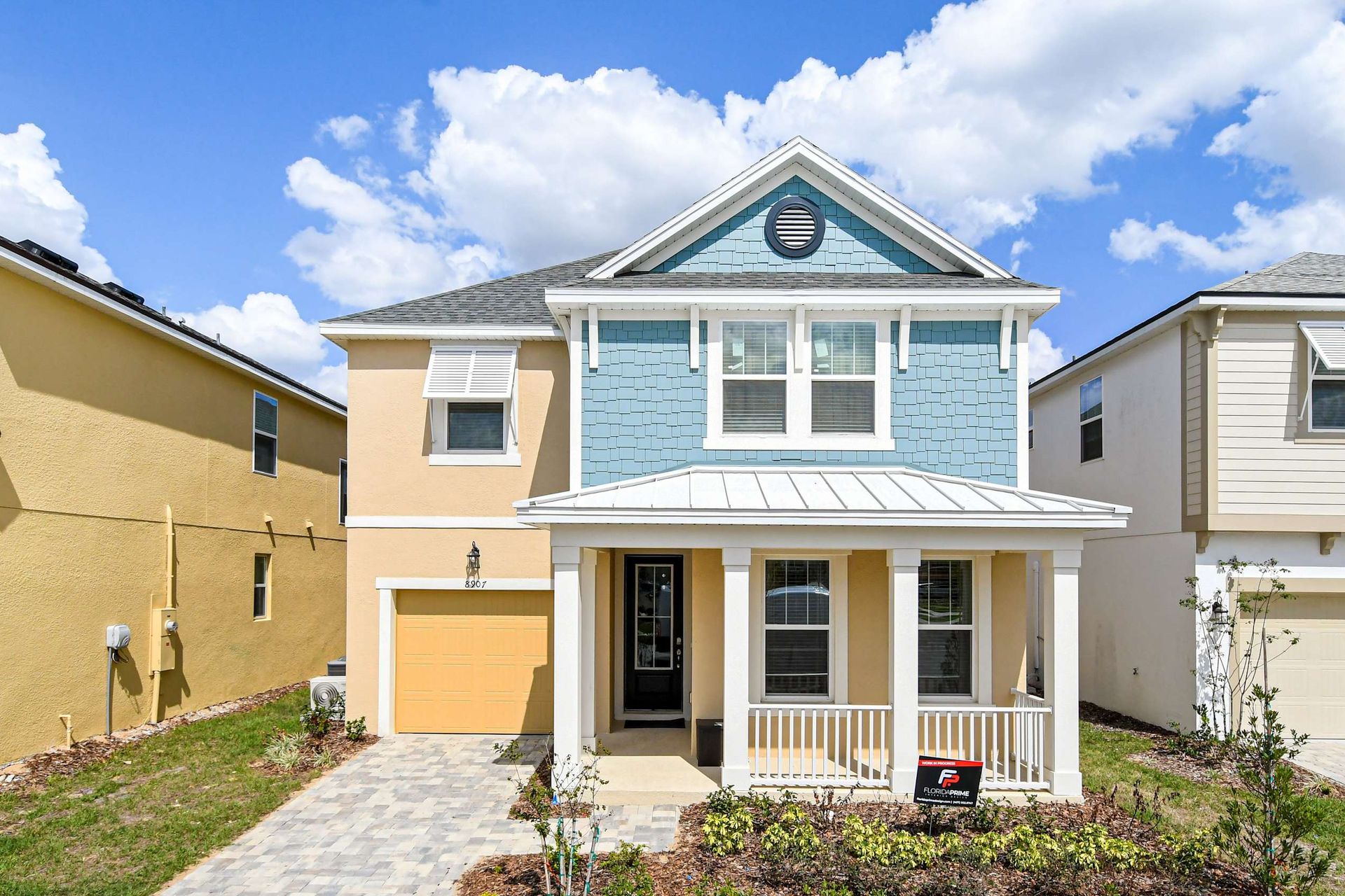 Charming two-story home with a porch, modern facade, and paved driveway.