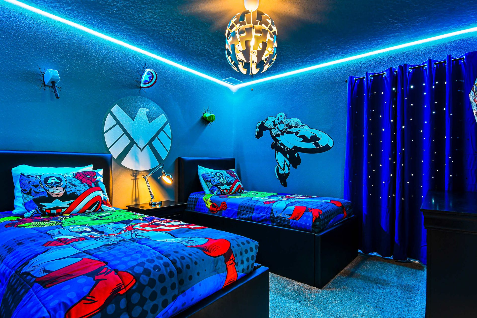 Superhero-themed bedroom with vibrant lighting, custom decor, and twin beds.