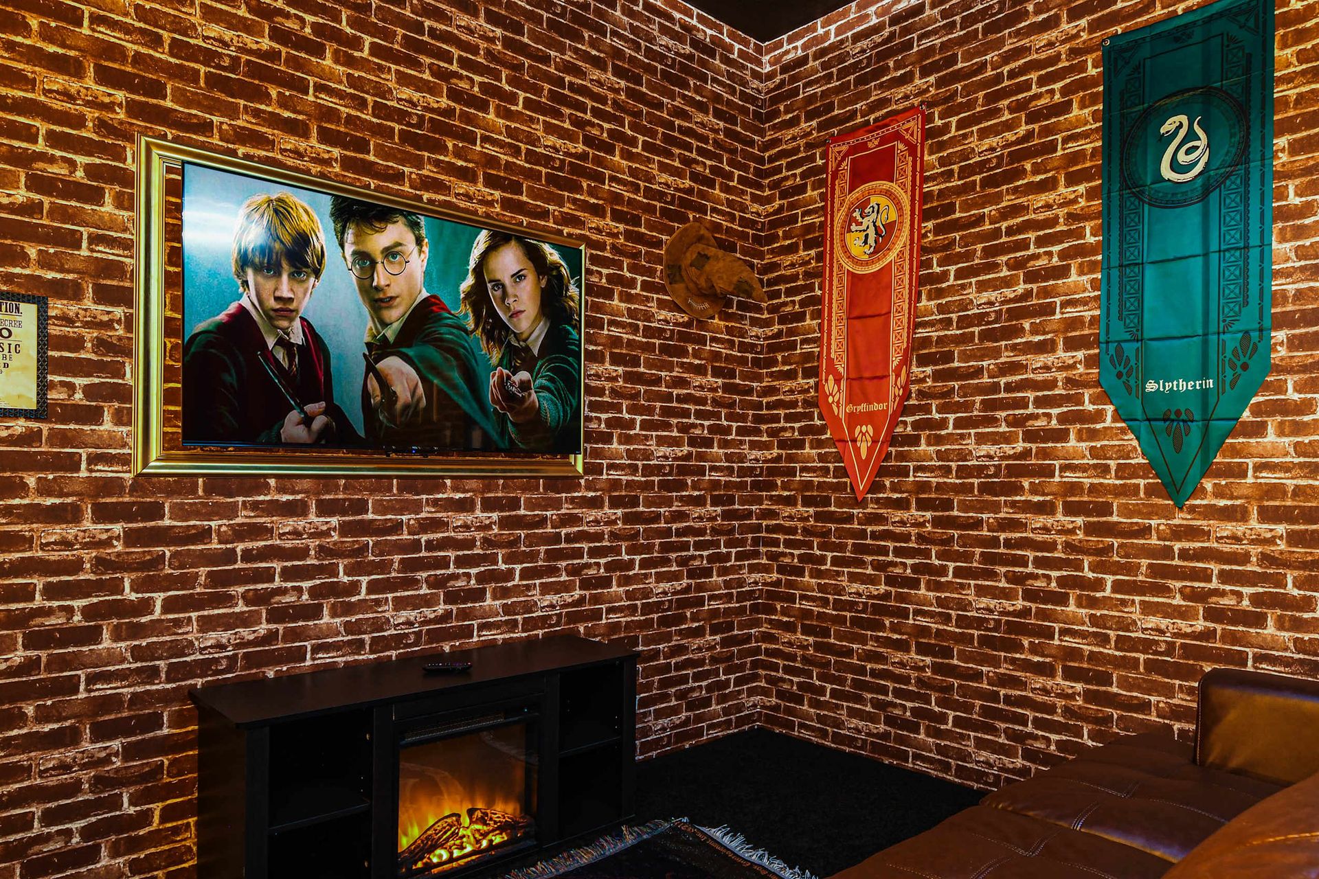 Cozy wizard-themed theater room with house banners, glowing fireplace, and comfy seating.
