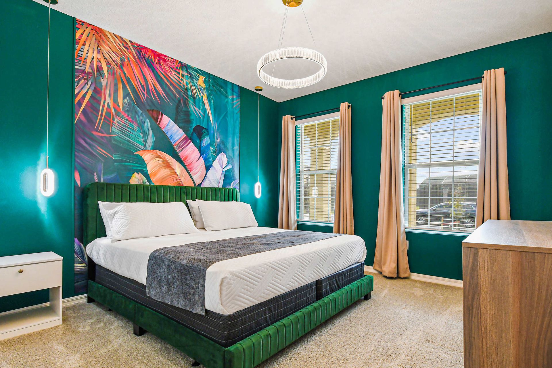 Vibrant bedroom with tropical mural, plush green bed, chic lighting, and TV setup.