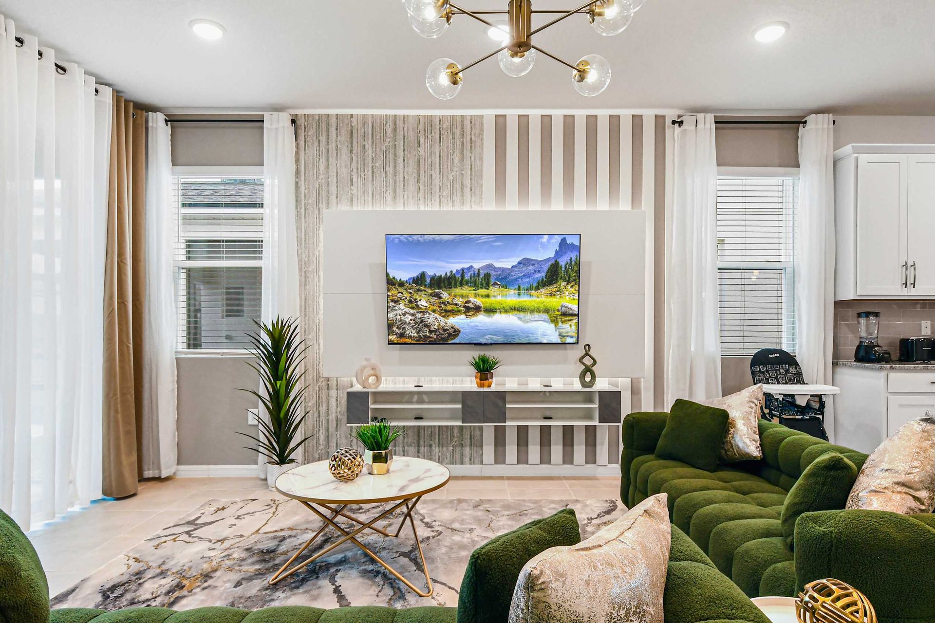 Chic modern living room with plush green seating and sleek kitchen access nearby.