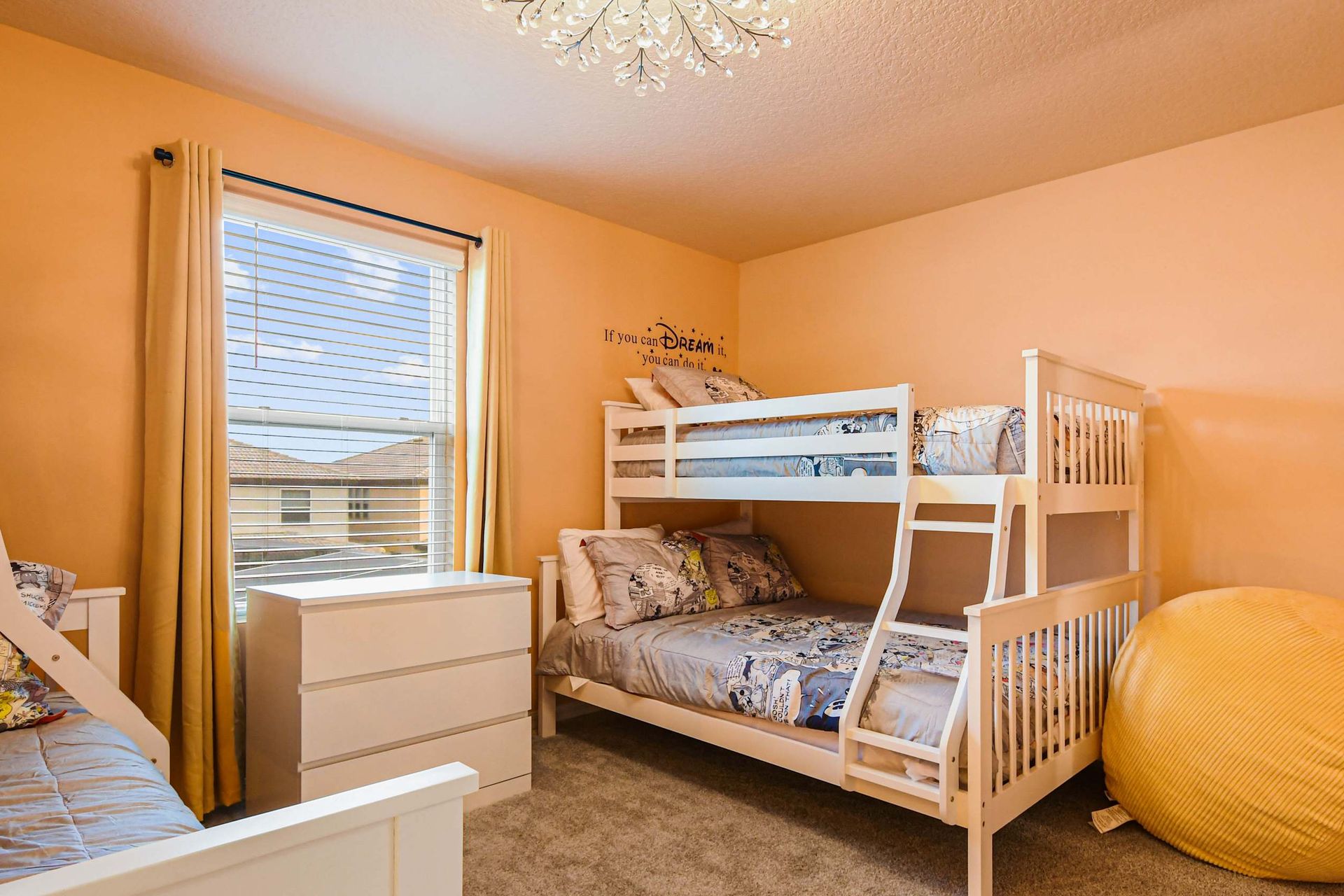 Cheerful kids’ room with bunk beds, playful bedding, and a cozy yellow beanbag chair.