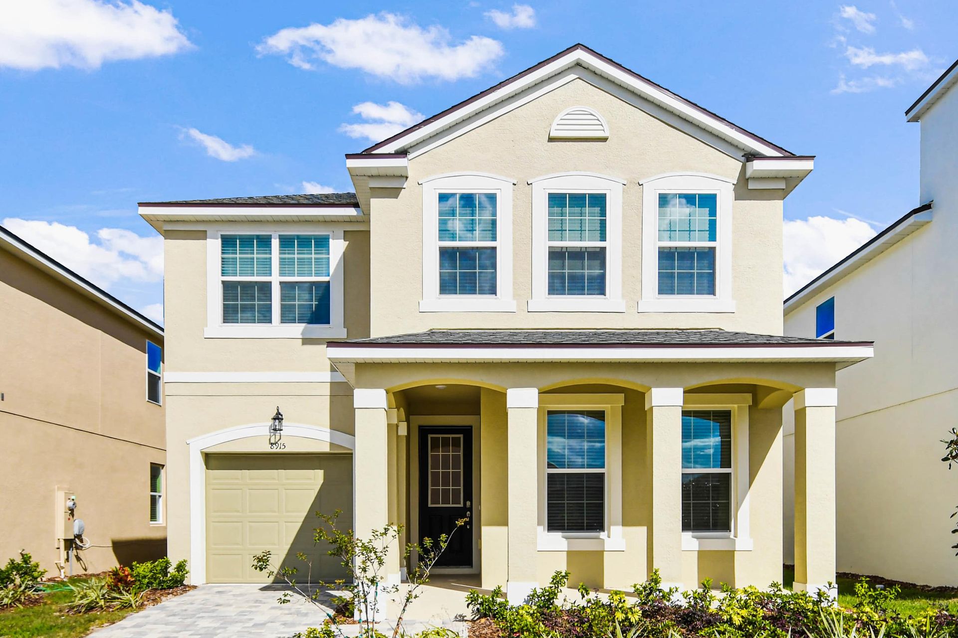 Beautiful modern two-story home with bright exterior, charming porch, and garage.