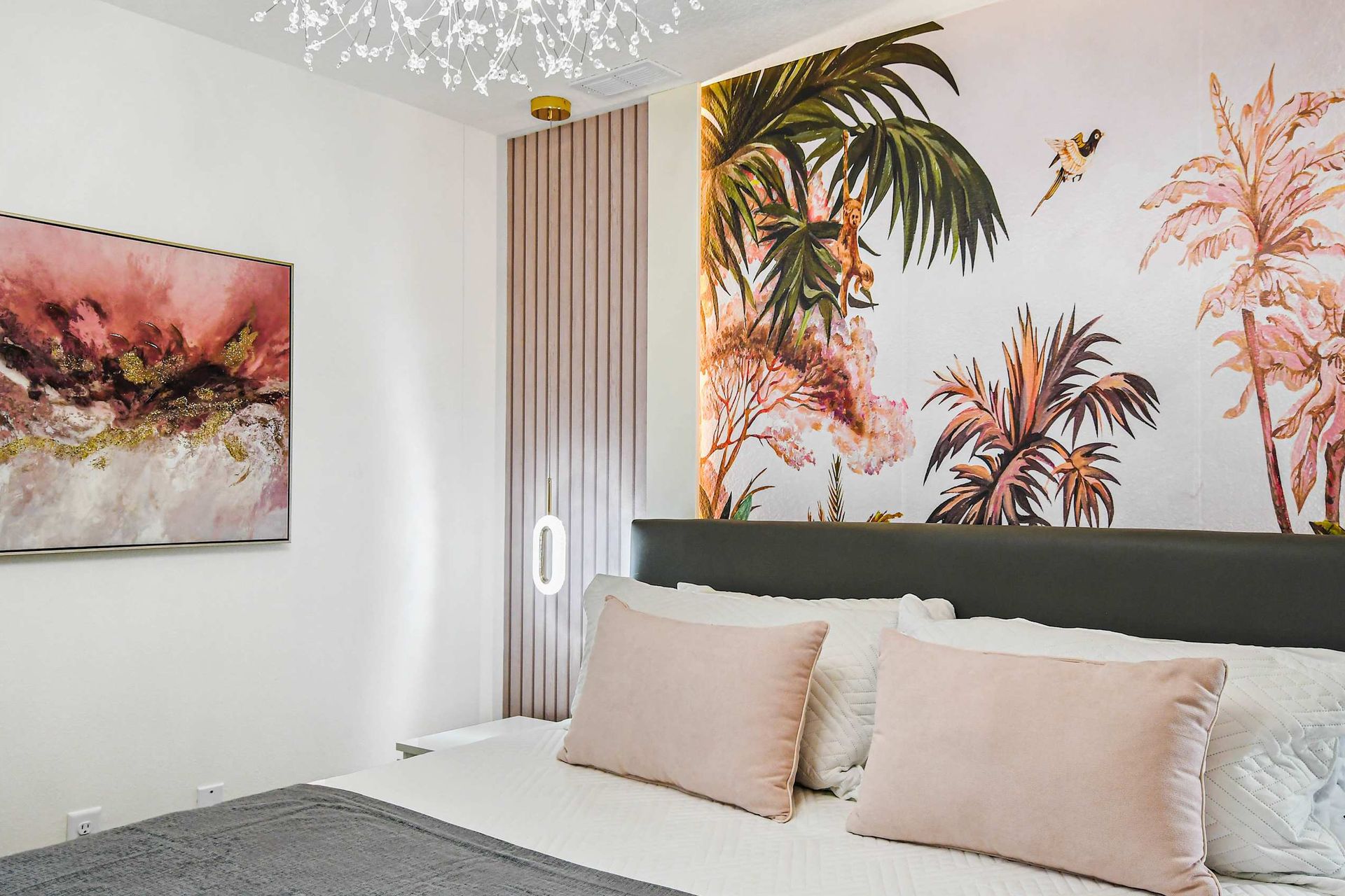 Chic bedroom with soft blush tones, tropical mural, elegant art, and cozy bedding.