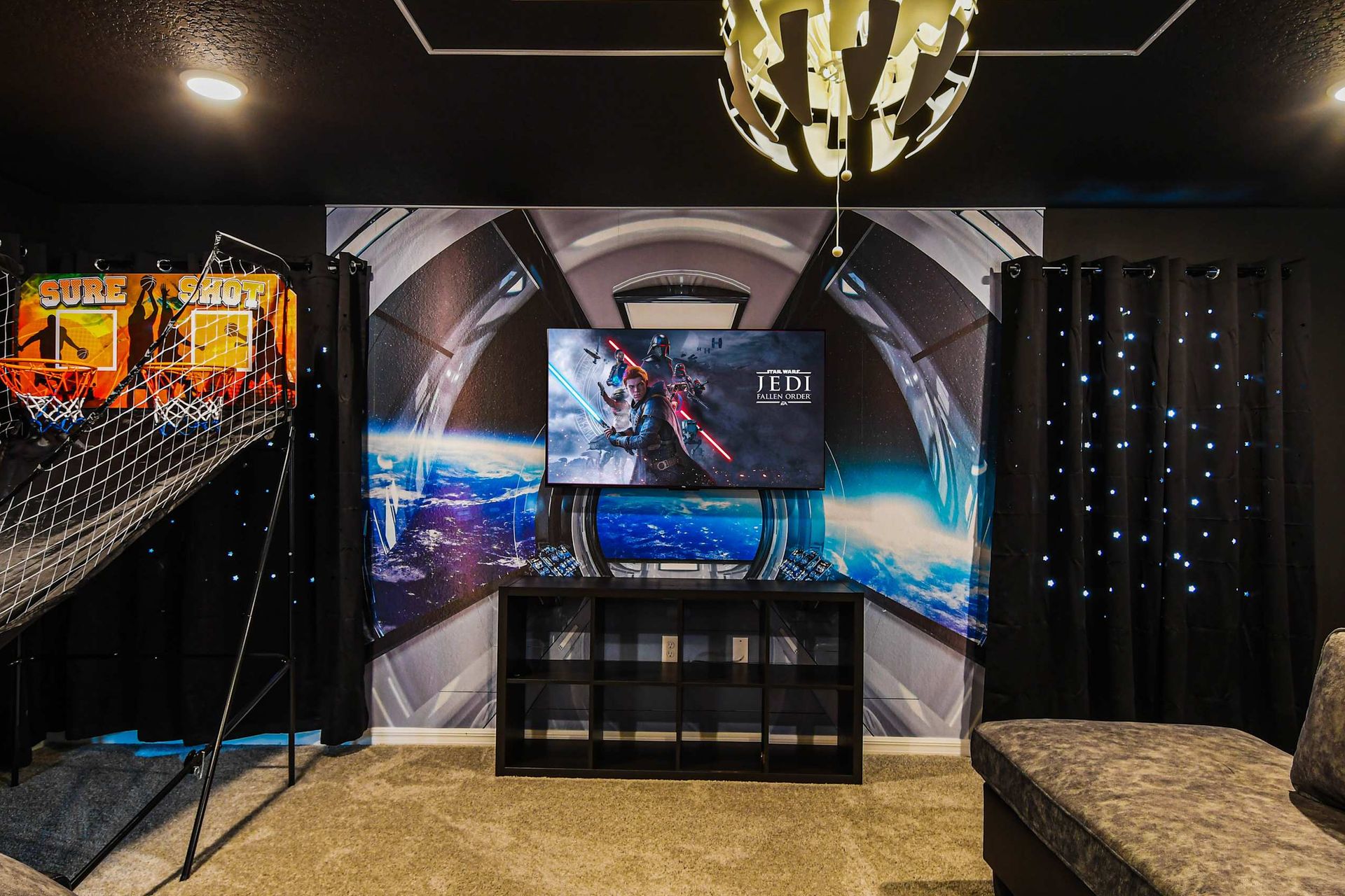 Thrilling game room with space-themed walls, arcade basketball, and gaming setup.