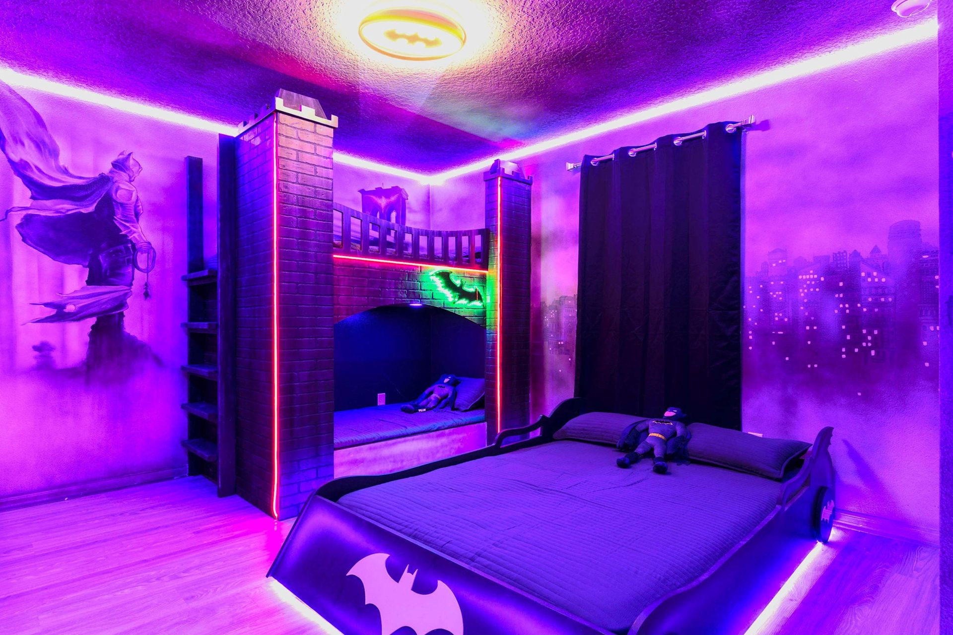Gotham-themed room with Batmobile bed, cityscape walls, & glow!