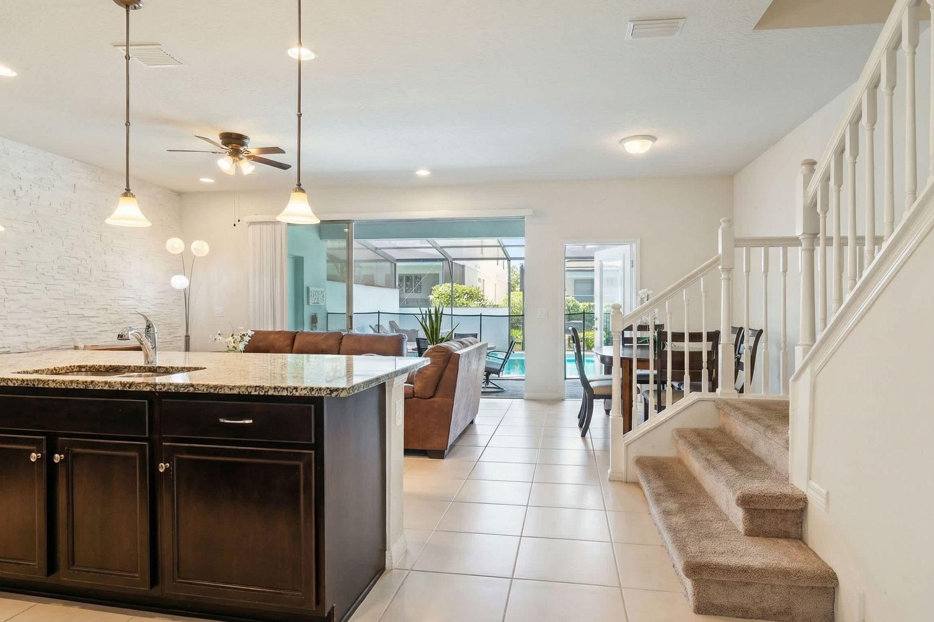Bright open layout with kitchen, dining, and living areas flowing to the pool patio.