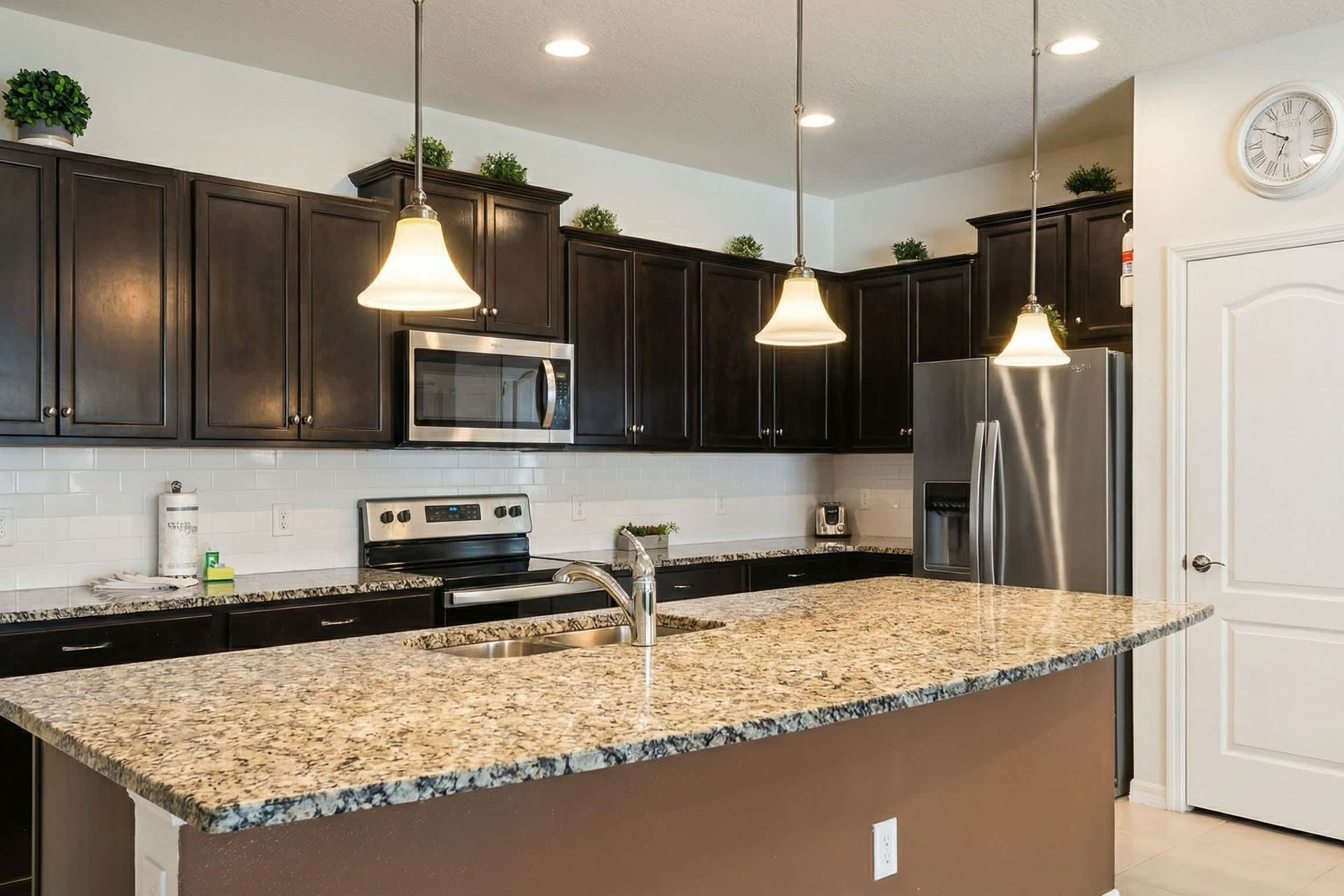 Spacious kitchen with granite island, dark wood cabinetry, and stainless appliances.