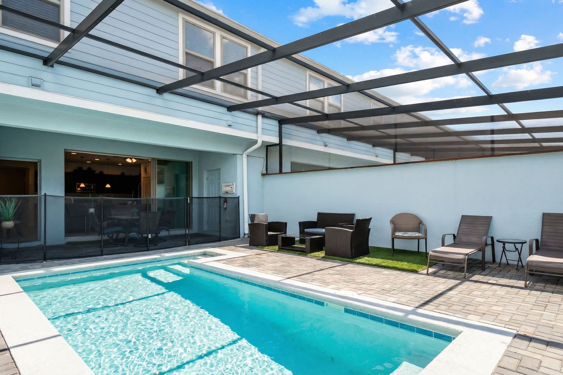 Family-friendly screened pool with lounge chairs, seating area, and safety fencing.