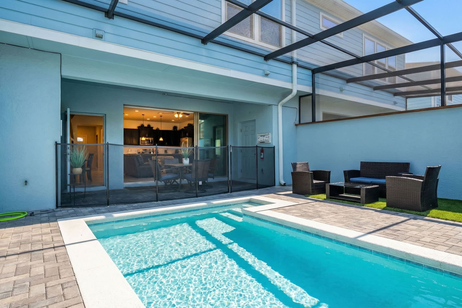 Spacious screened pool area with safety gate, outdoor dining, and cozy lounge seating.