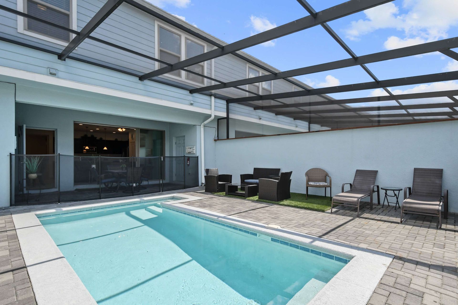 Family-friendly screened pool with lounge chairs, seating area, and safety fencing.