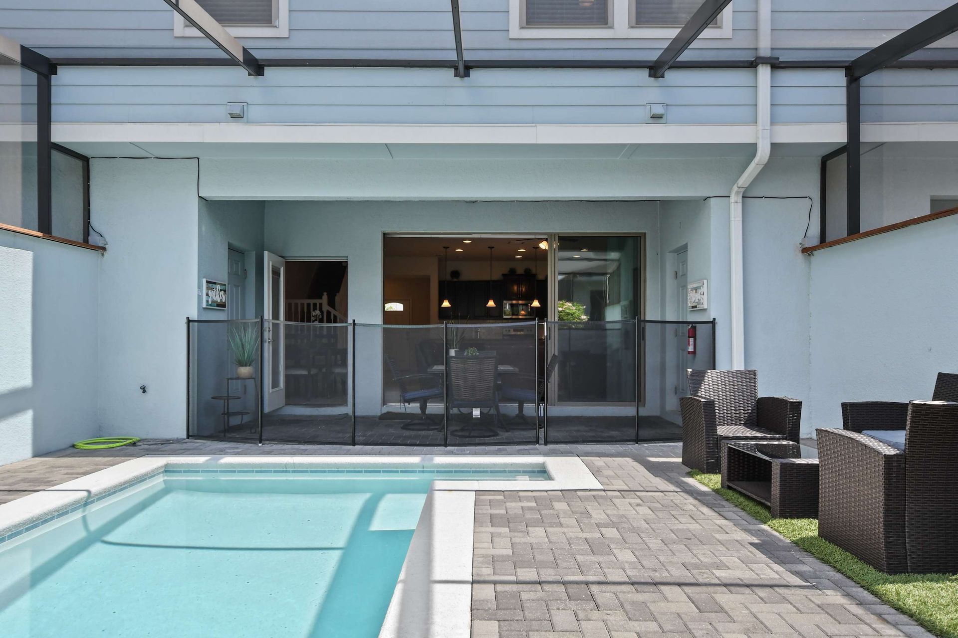 Spacious screened pool area with safety gate, outdoor dining, and cozy lounge seating.