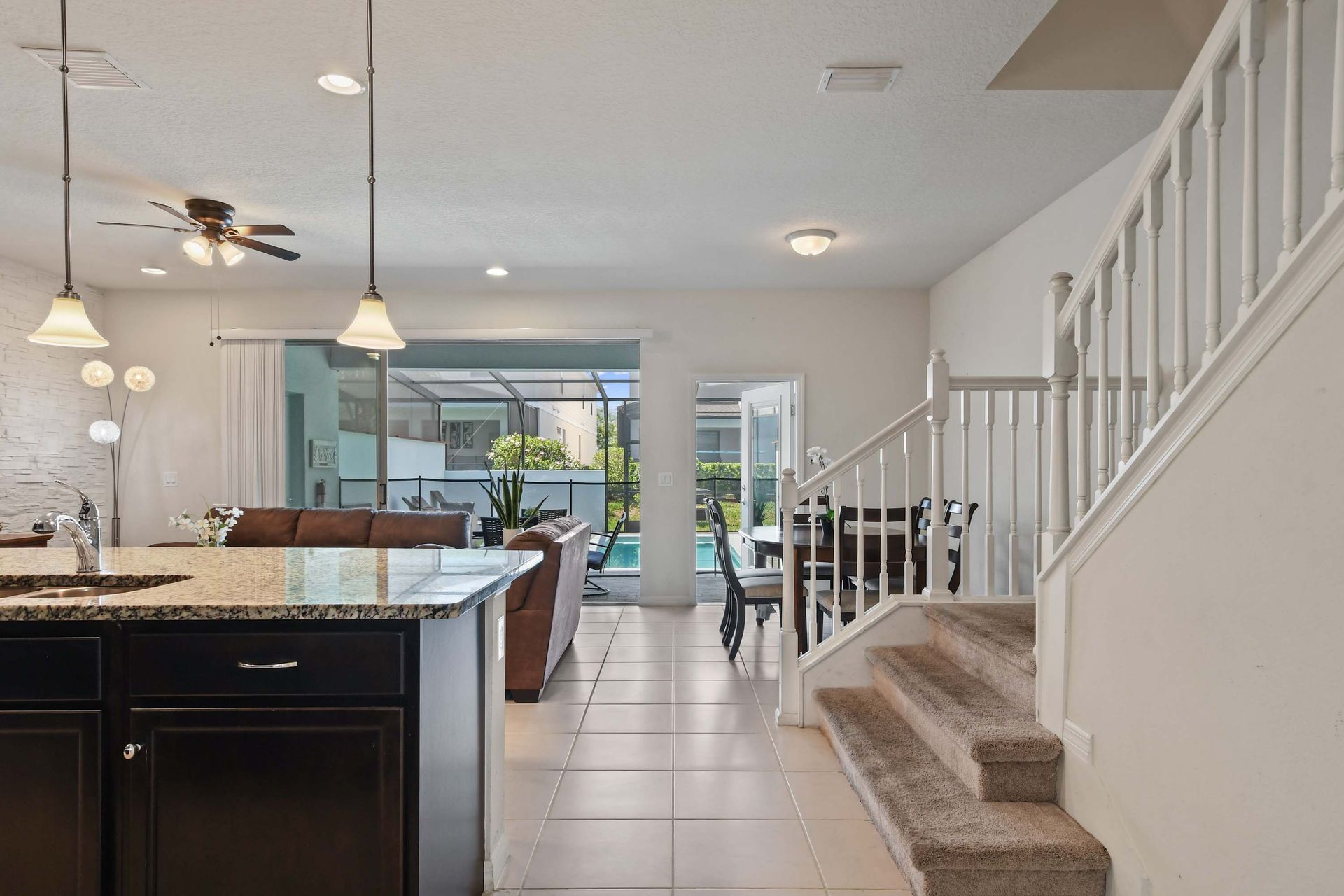 Bright open layout with kitchen, dining, and living areas flowing to the pool patio.