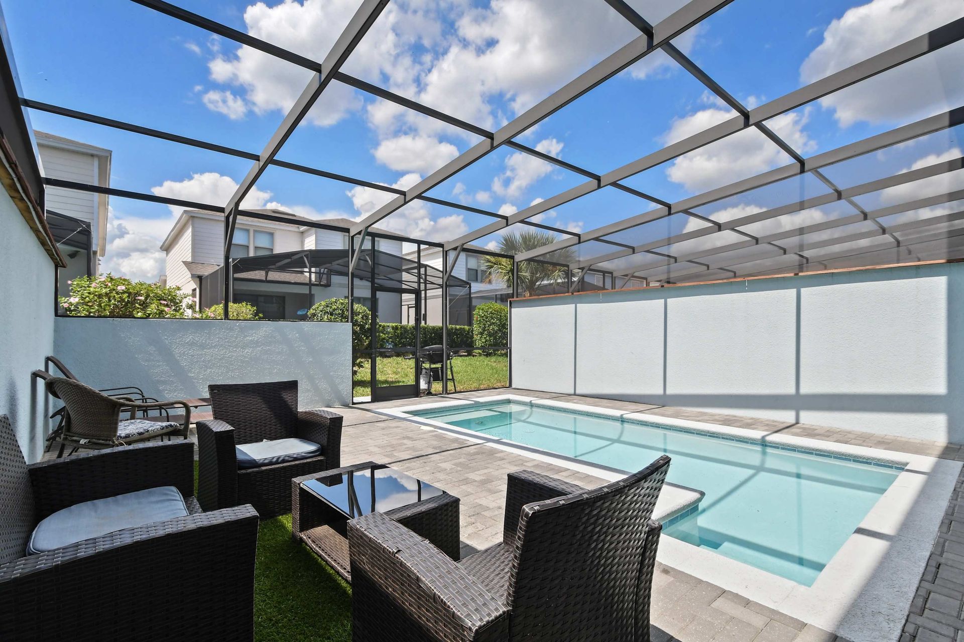 Relax in the private screened pool with stylish outdoor seating under sunny skies.