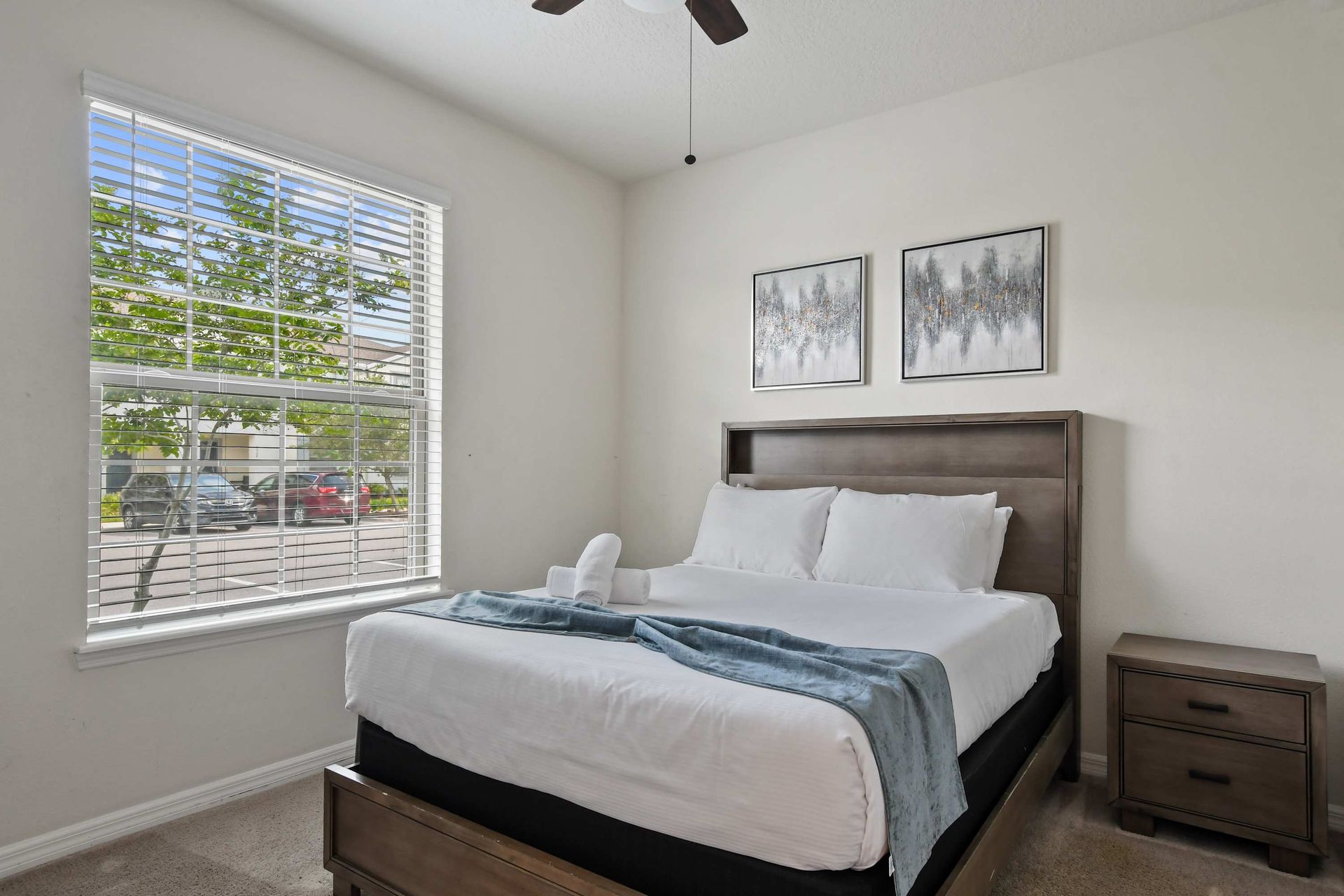 Bright and serene queen bedroom with modern décor and a peaceful street view.
