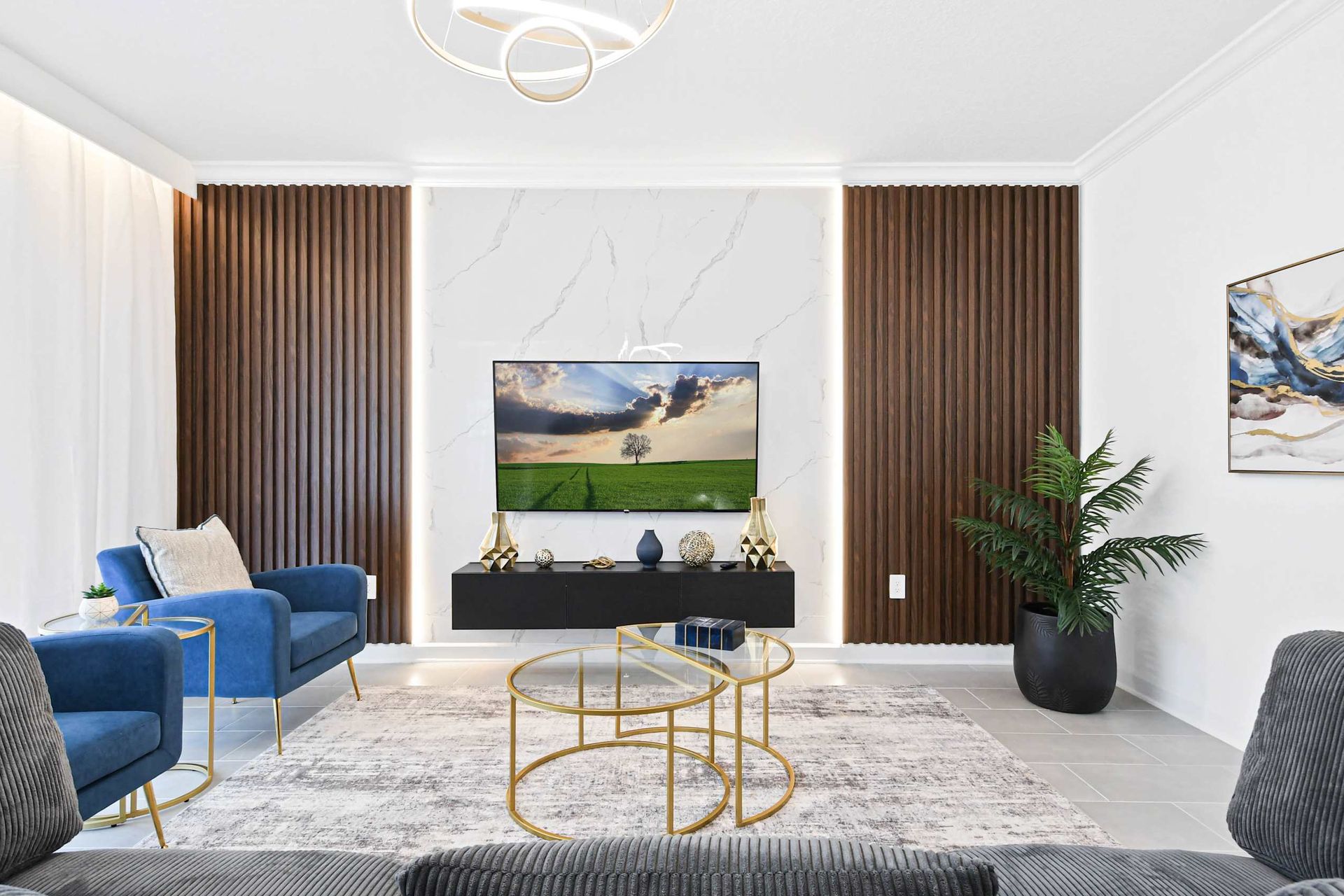 Chic living room with plush seating, gold accents, modern art, and a smart TV.