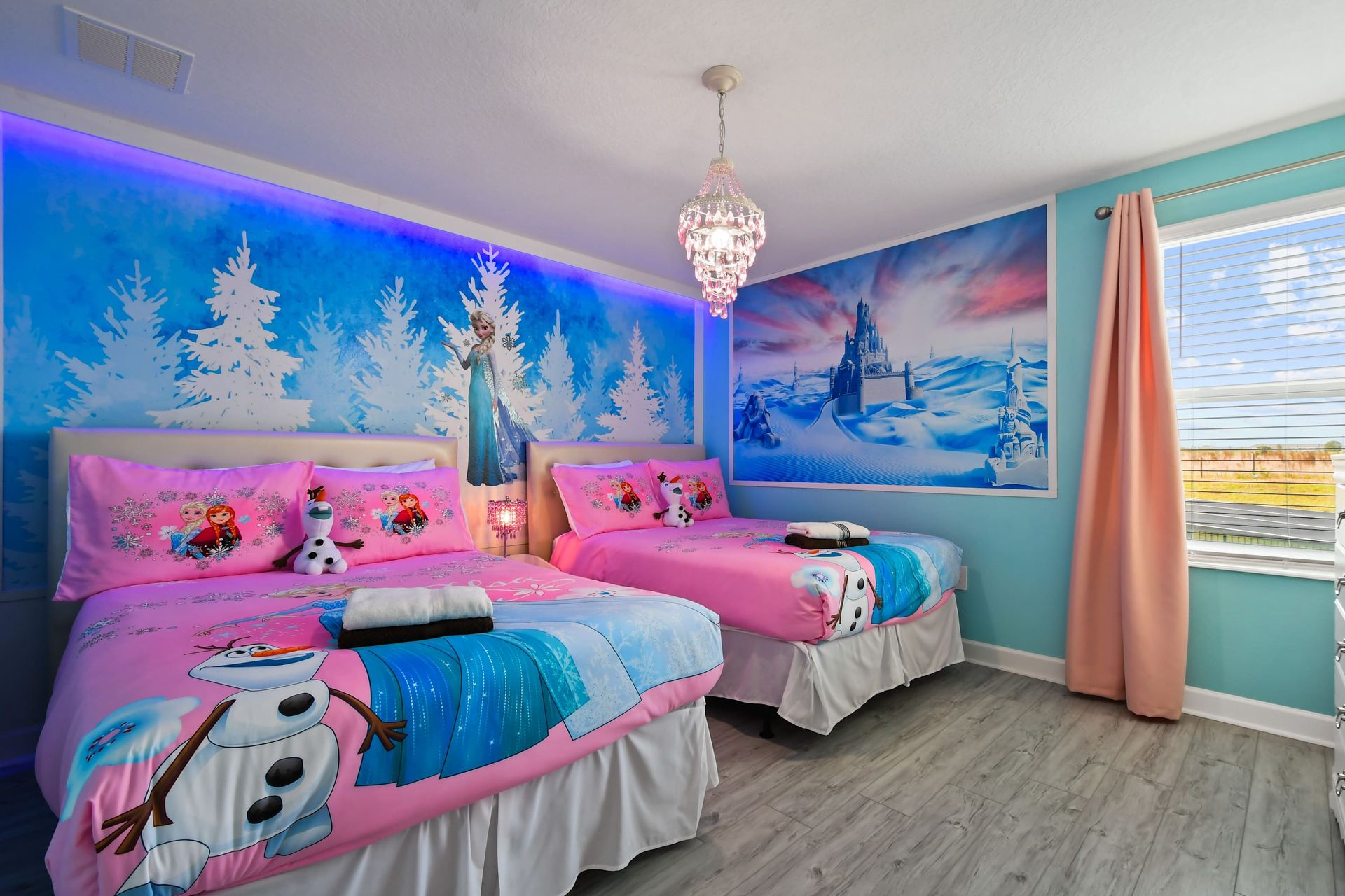 Magical winter princess room with themed bedding, chandelier, and icy wall art.