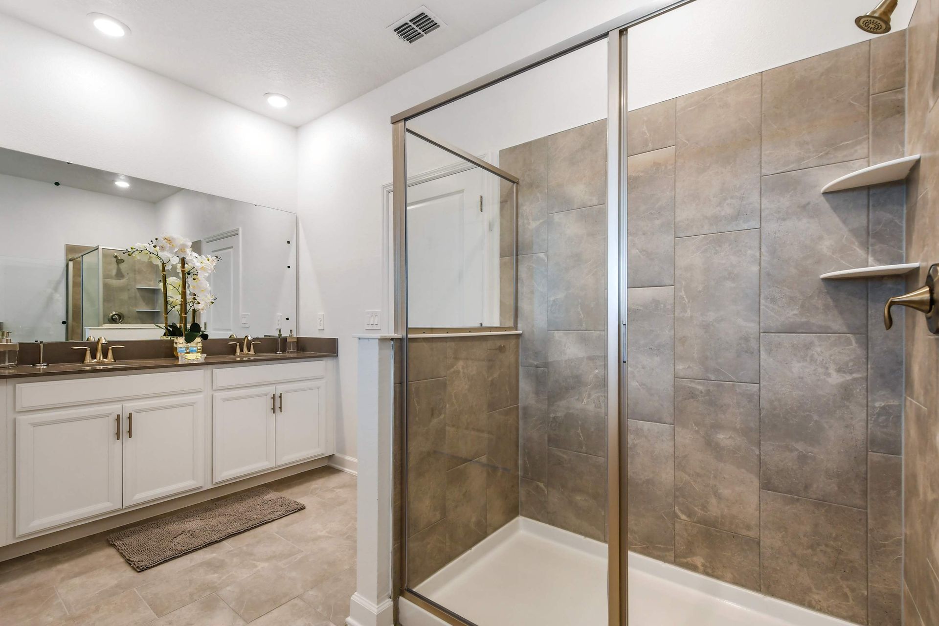 Spacious bathroom with elegant double sinks and a large walk-in glass shower.