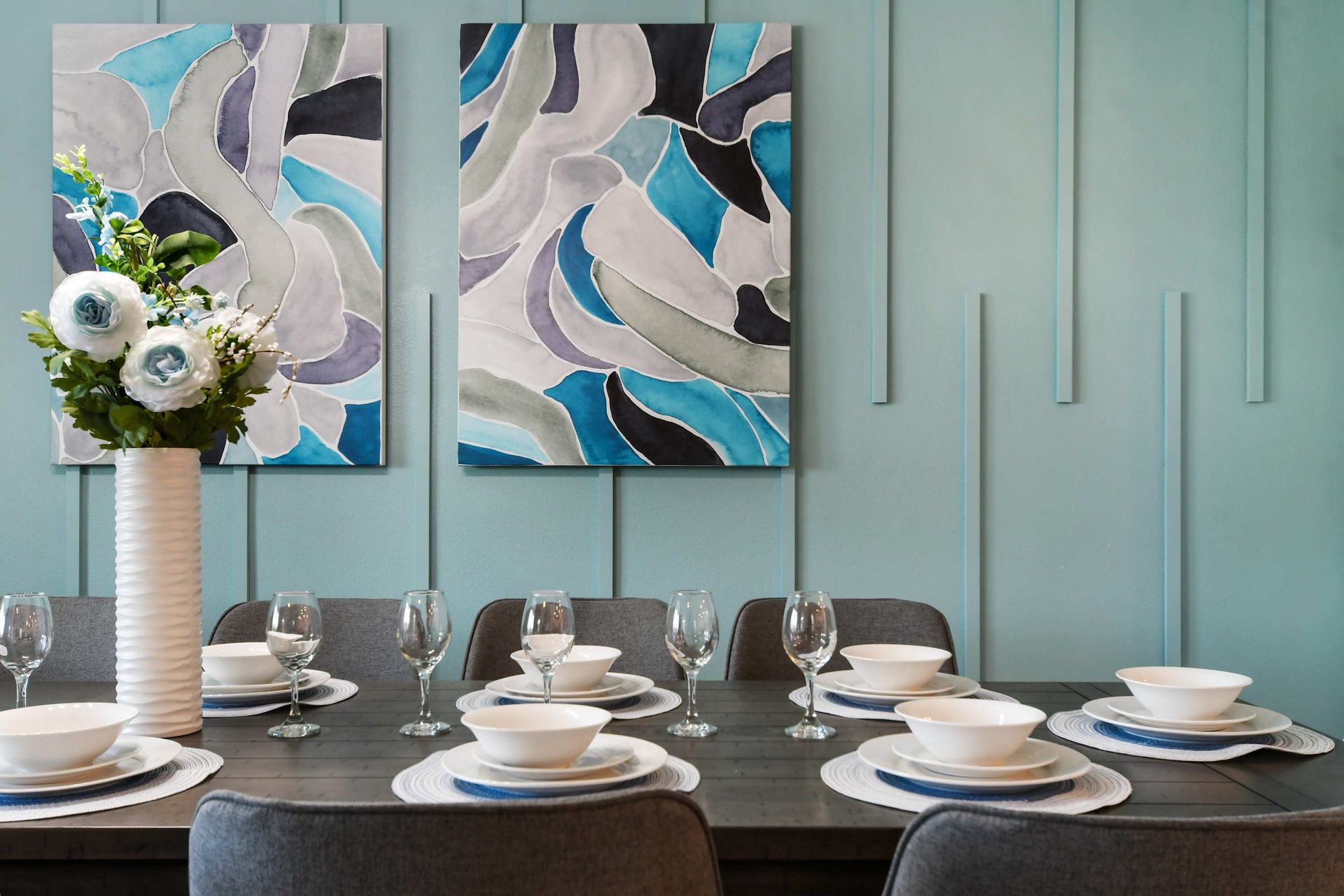 Elegant dining setup with modern art, stylish tableware, and soft blue accents.