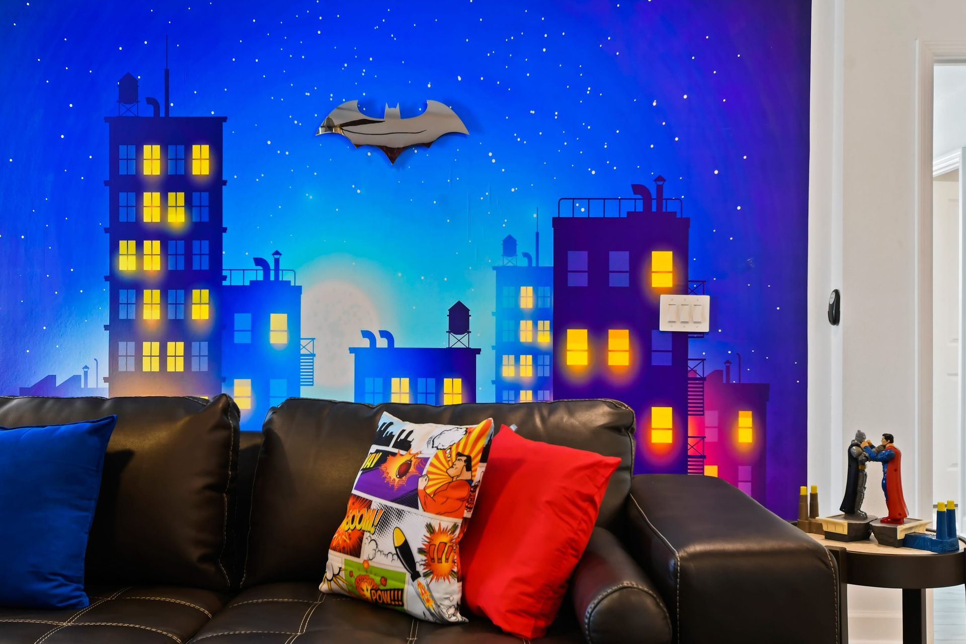 Colorful hero-themed wall with cityscape mural, comic pillows, and action figures.