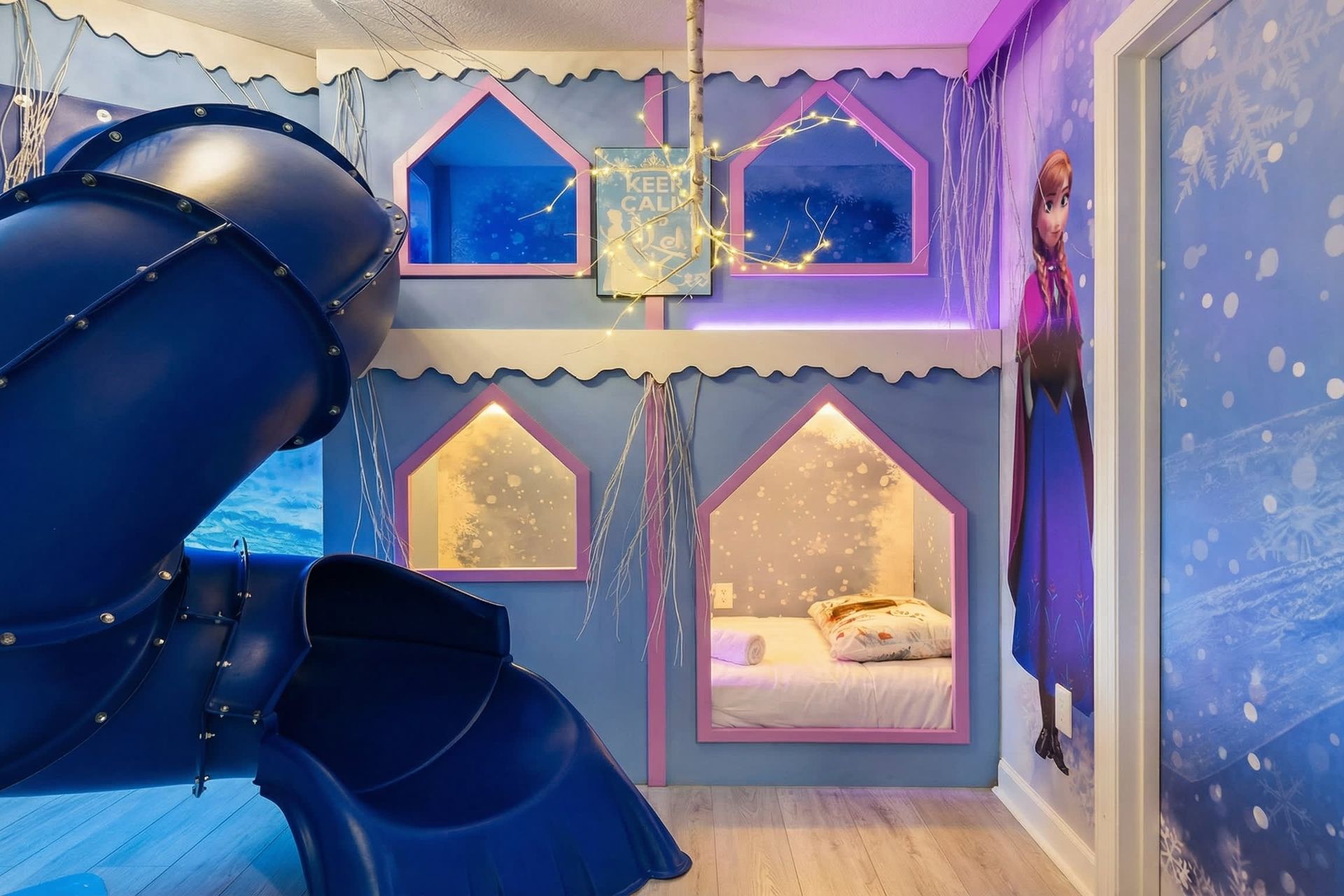 Magical winter-themed bunk room with glowing lights, an icy slide, and cozy beds.