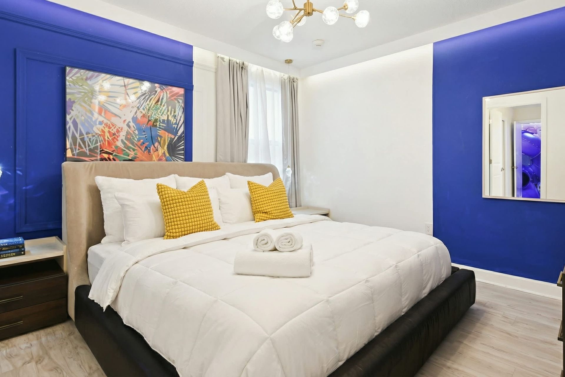 Vibrant and stylish bedroom with a plush king bed, bold blue accents, and modern lighting.