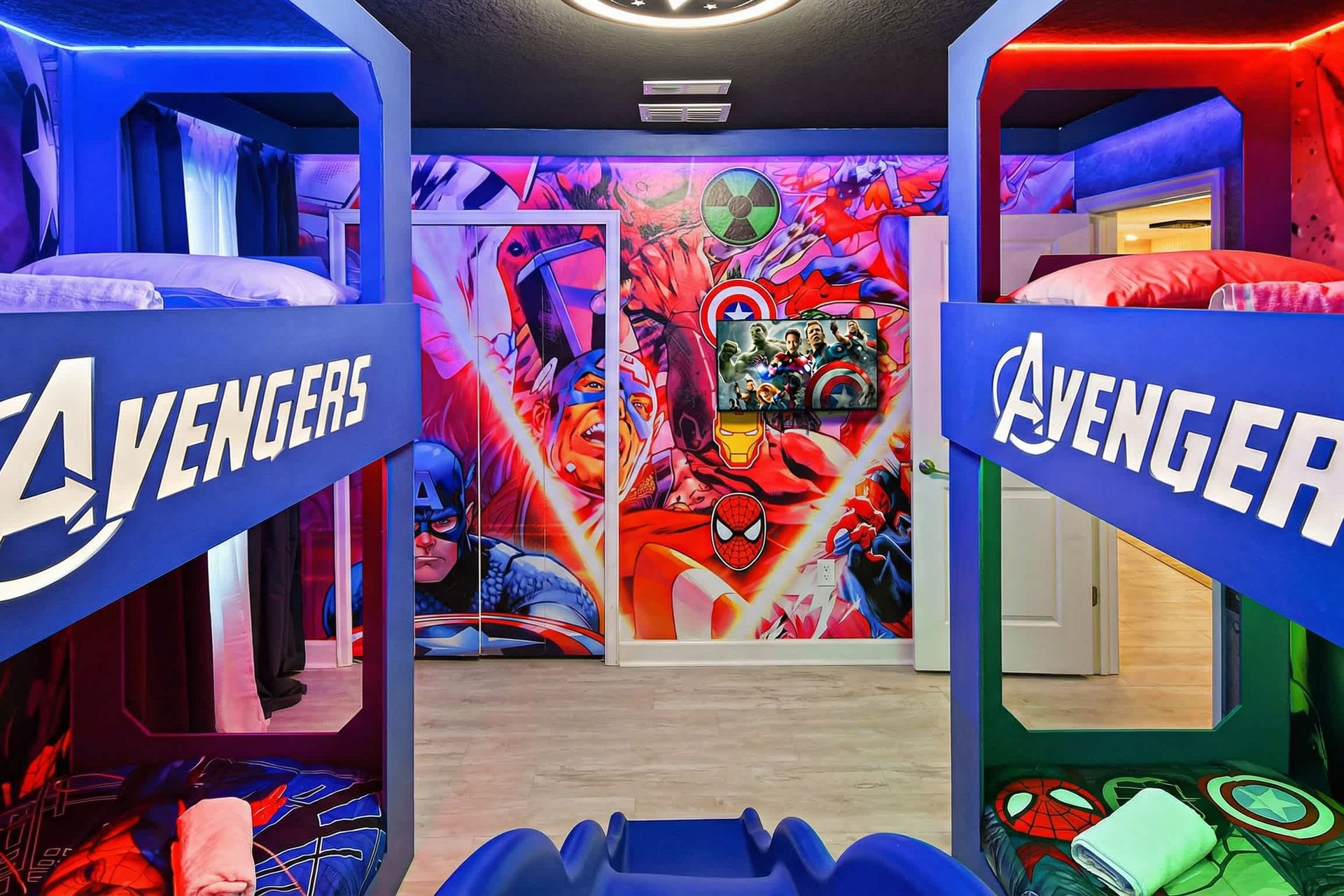 Action-packed Avengers-themed bunk room with bold murals, glowing lights, and a slide.