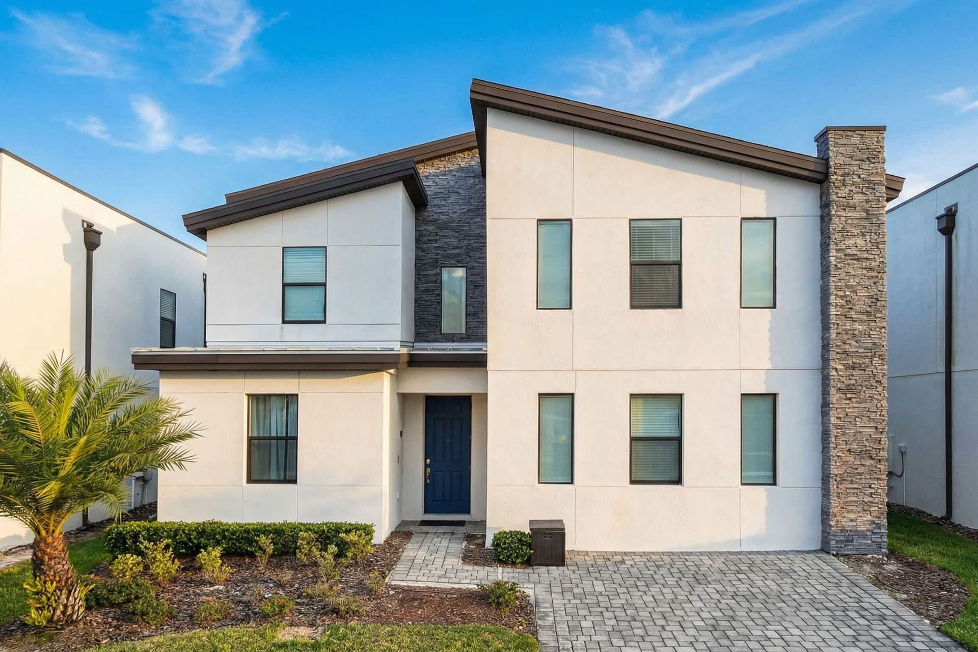 Modern and sleek two-story home with a stone accent and well-maintained landscaping.