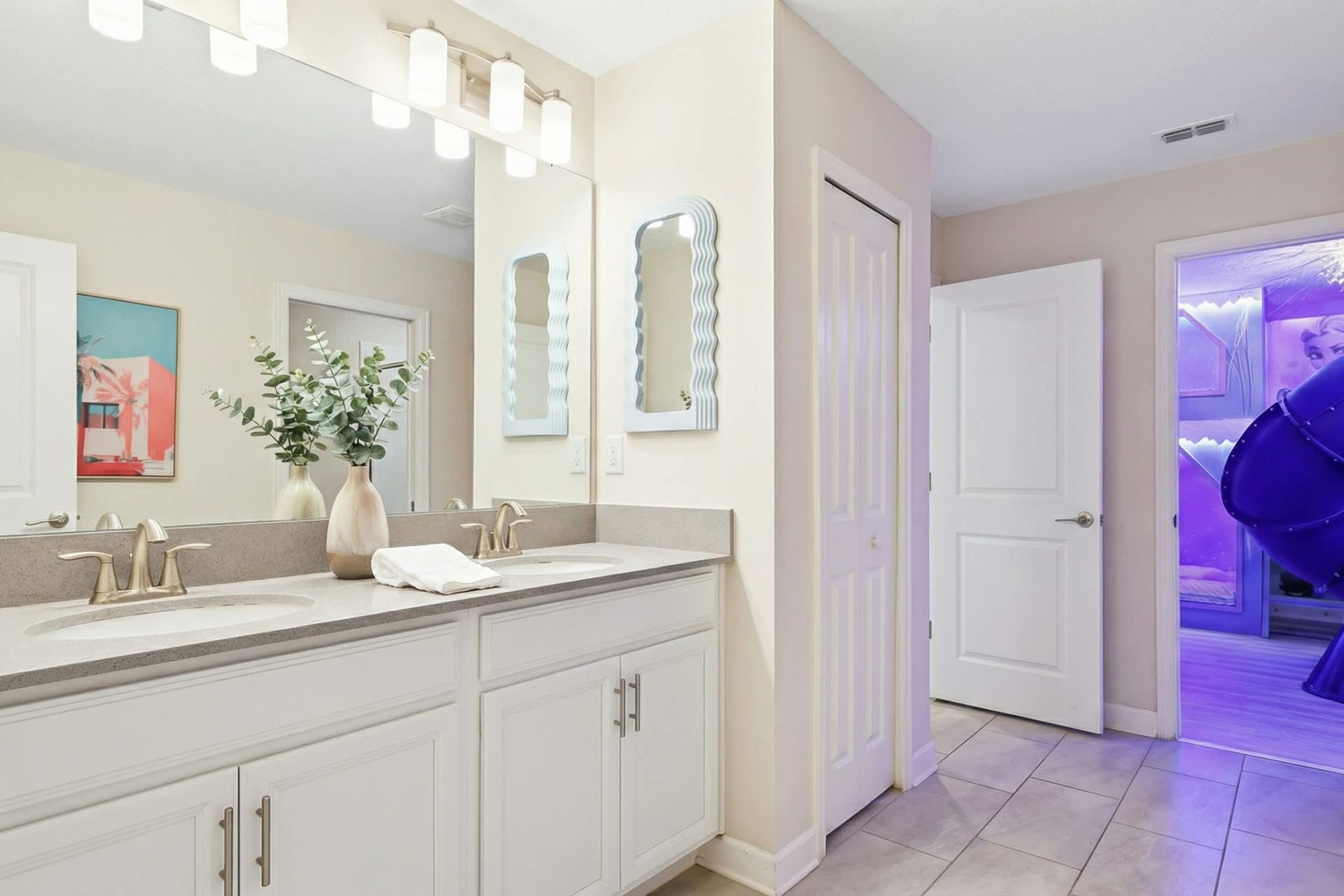 Bright and modern bathroom with a dual vanity, stylish mirrors, and a fun themed entryway.