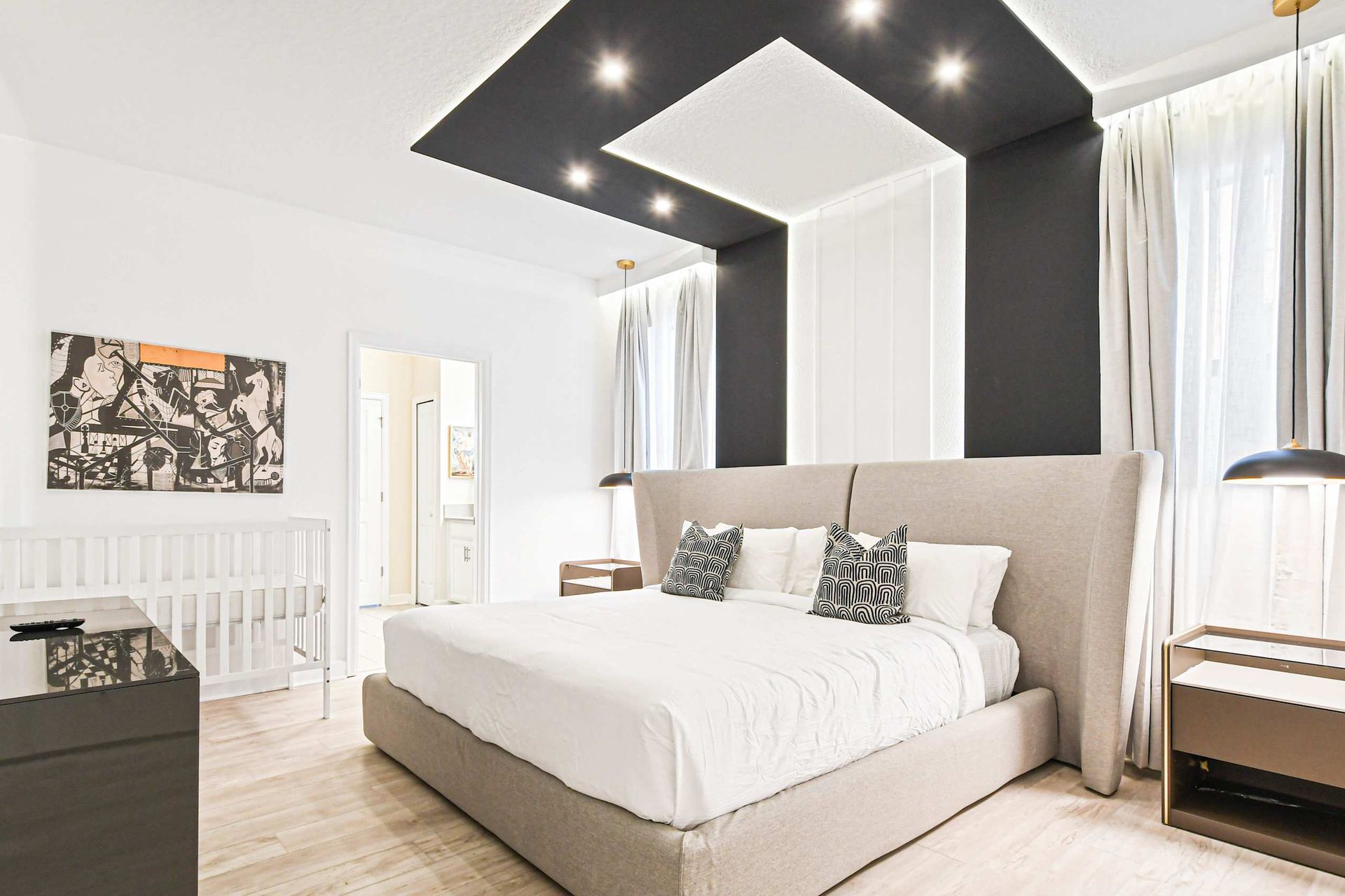 Stylish master suite with a luxe king bed, modern lighting, and a cozy crib setup.