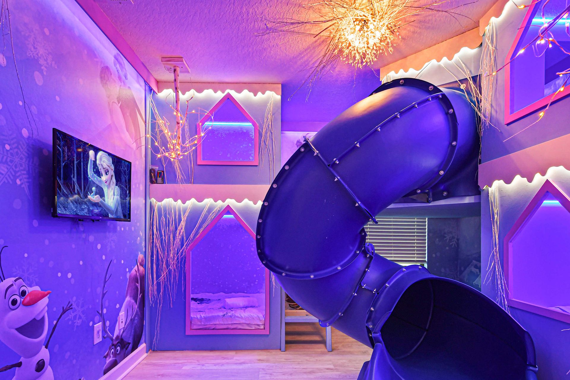 Magical winter-themed bunk room with glowing lights, an icy slide, and cozy beds.
