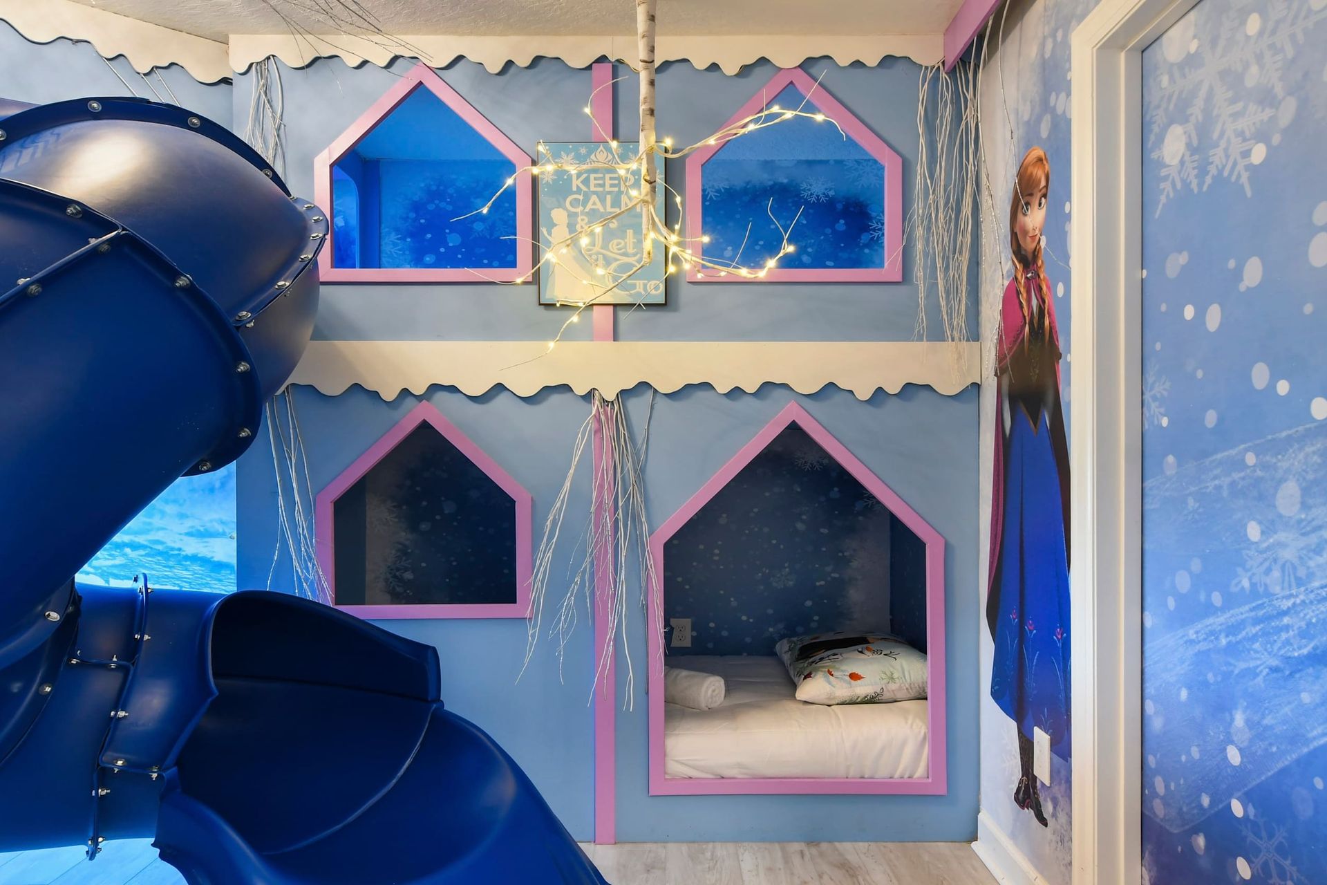Magical winter-themed bunk room with glowing lights, an icy slide, and cozy beds.