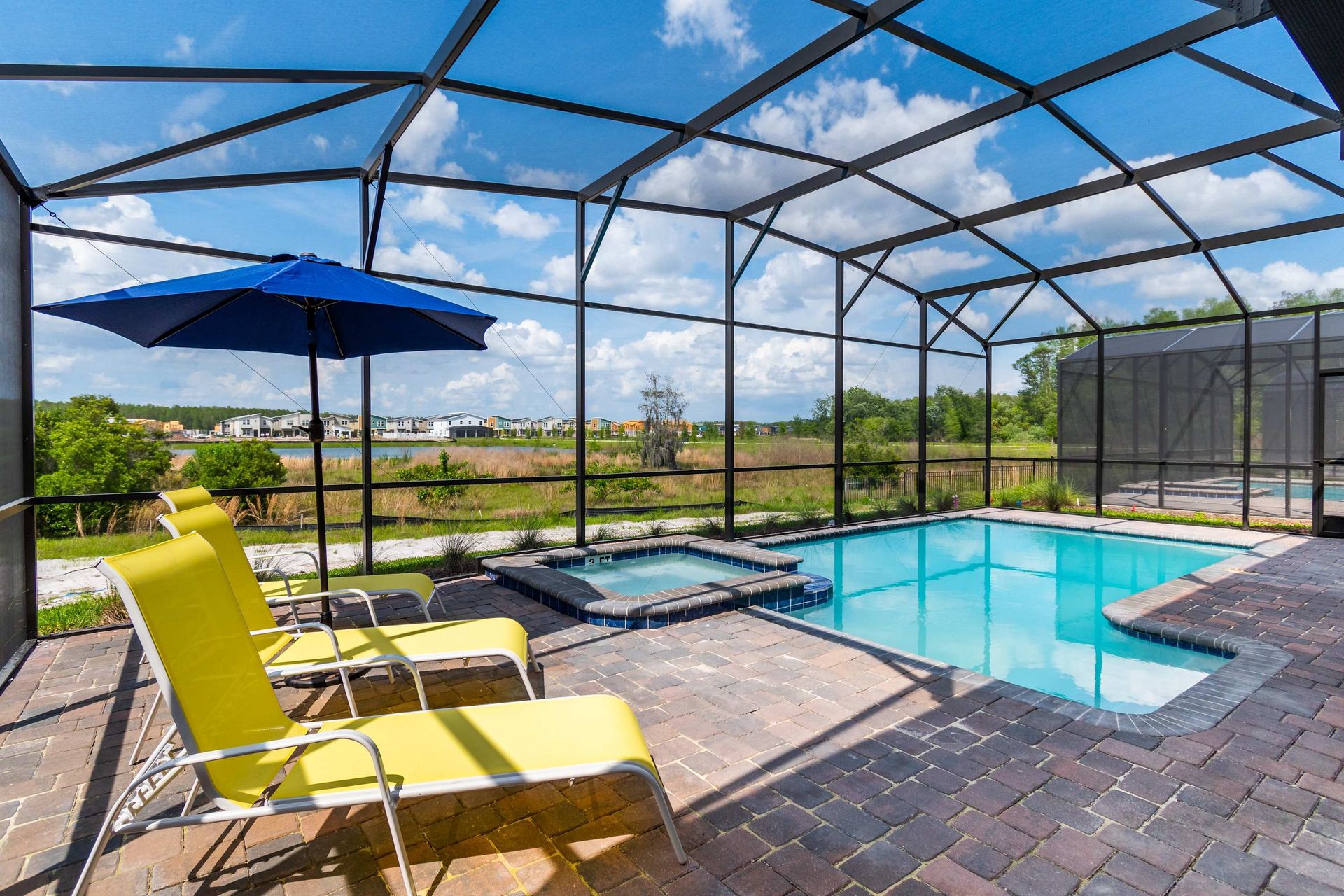 Private screened pool and spa with sunny loungers, serene view, and blue skies
