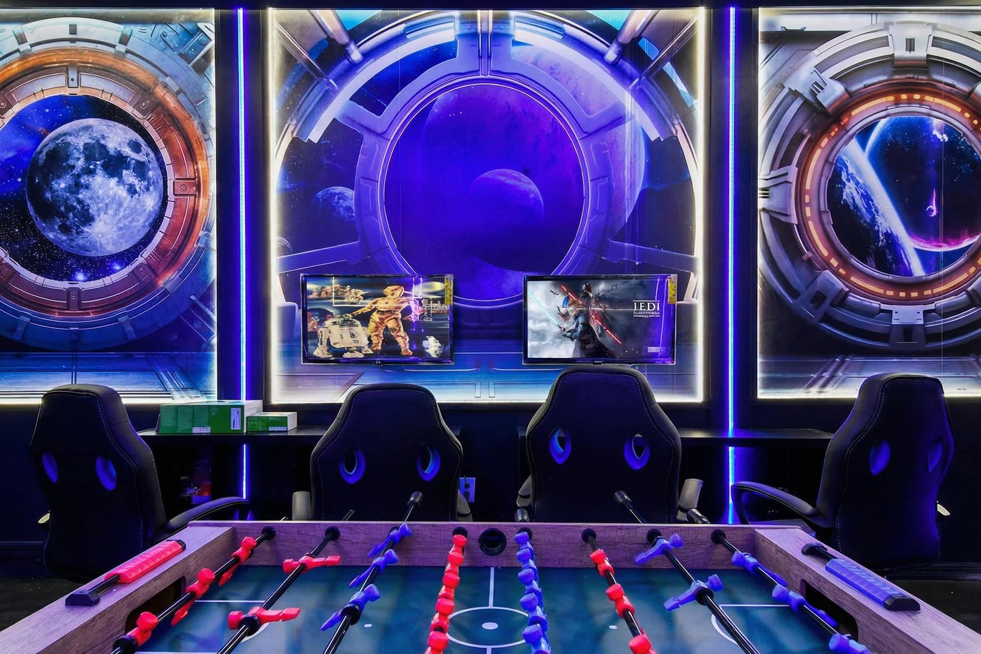 Space-themed gaming room with foosball, dual screens, and immersive galactic art.
