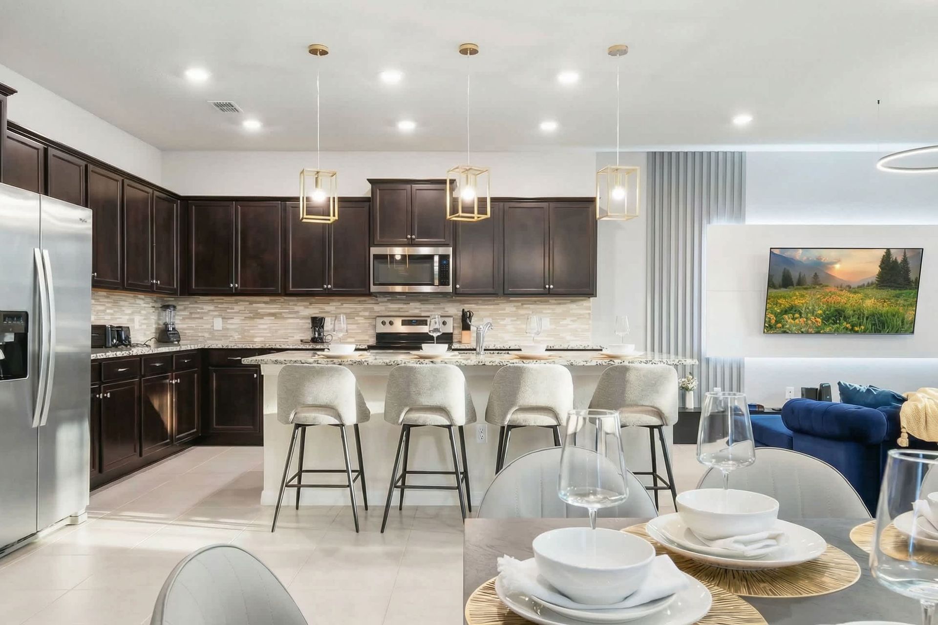 Chef’s kitchen with bar seating, designer lighting, and a cozy living room view.
