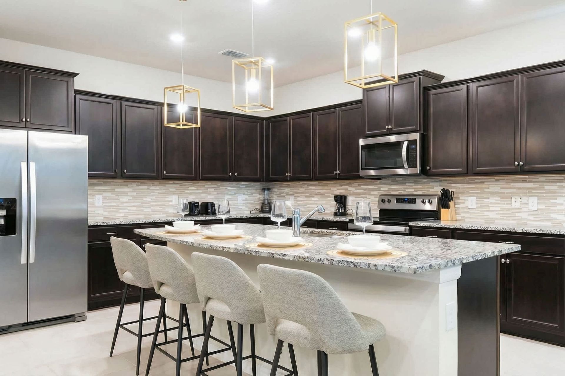 Modern kitchen with granite island, bar seating, and elegant pendant lighting.