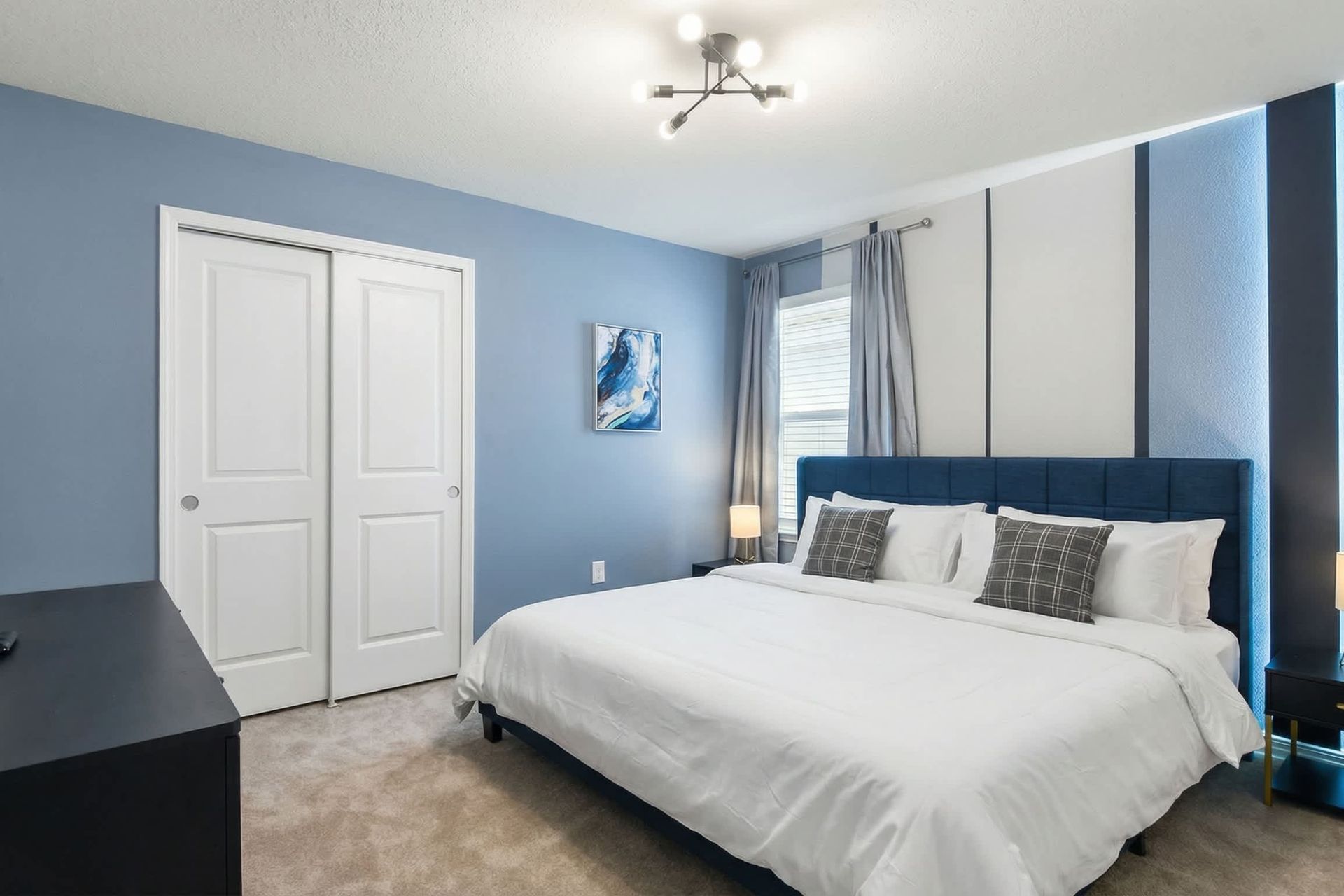 Sleek blue-accented bedroom with a king bed, modern lighting, and stylish decor.