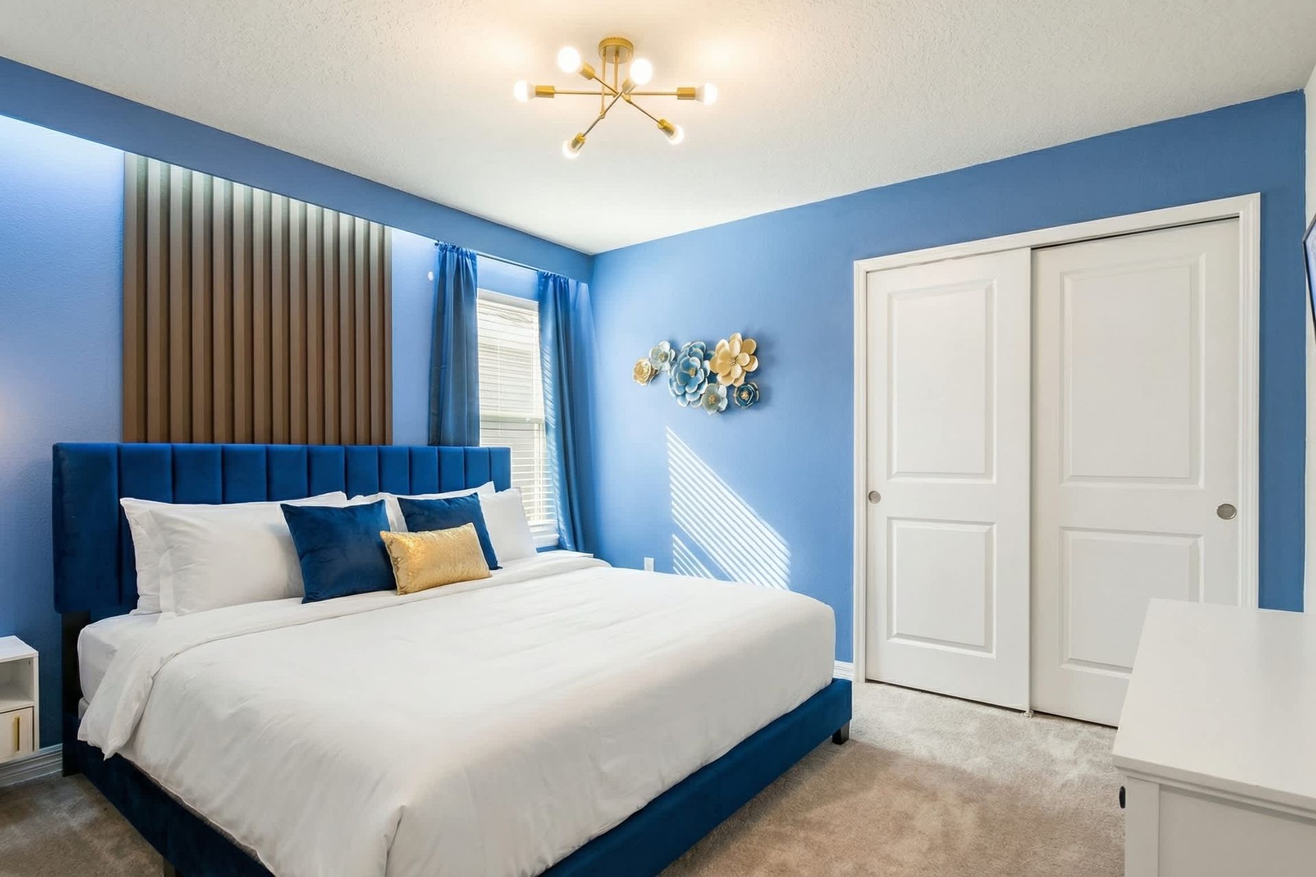 Vibrant blue bedroom with a king bed, glowing accent wall, and modern flair.