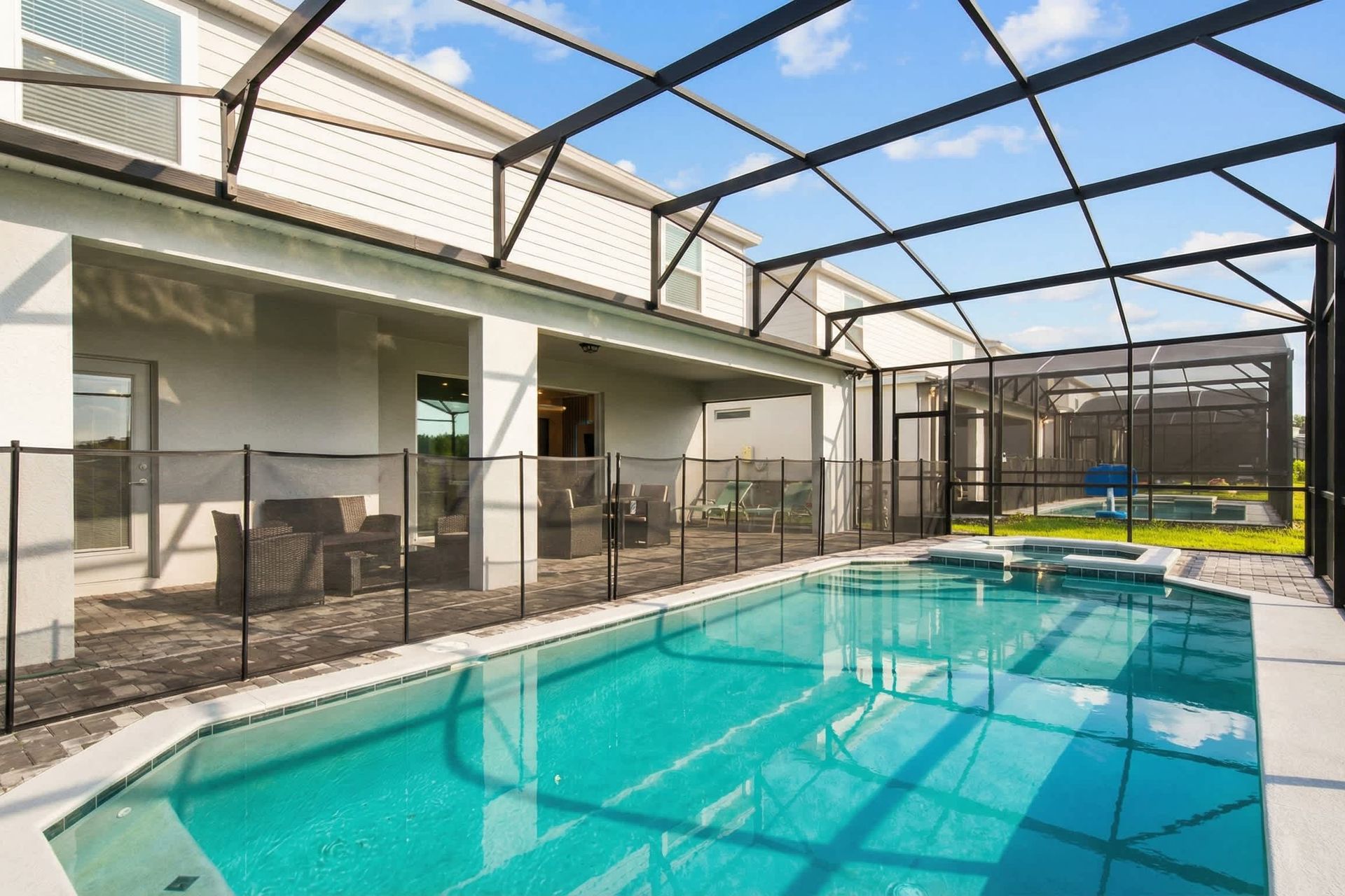 Screened-in pool and spa with spacious patio, perfect for family fun and relaxation.